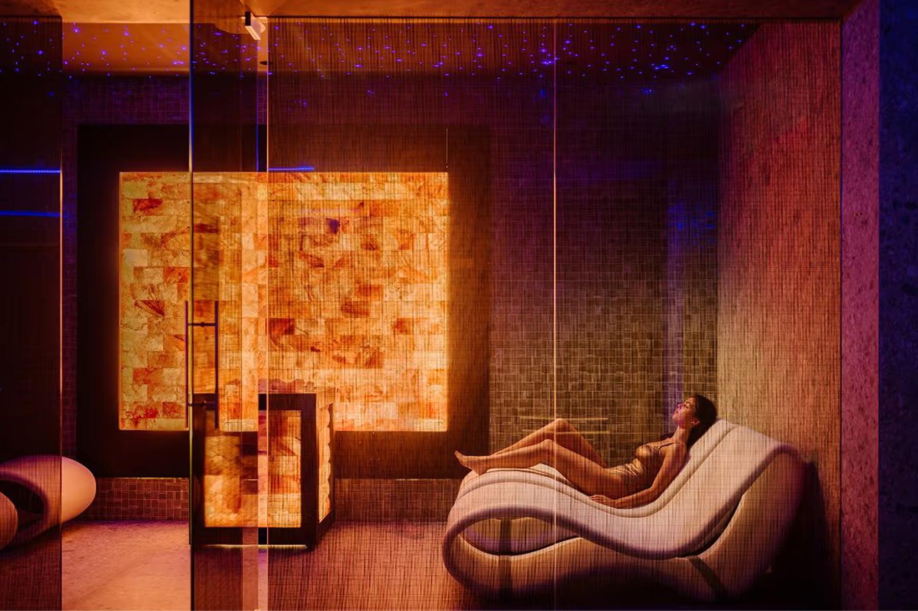 A lounge with warm orange-amber tones, sculptural furniture, and mood lighting