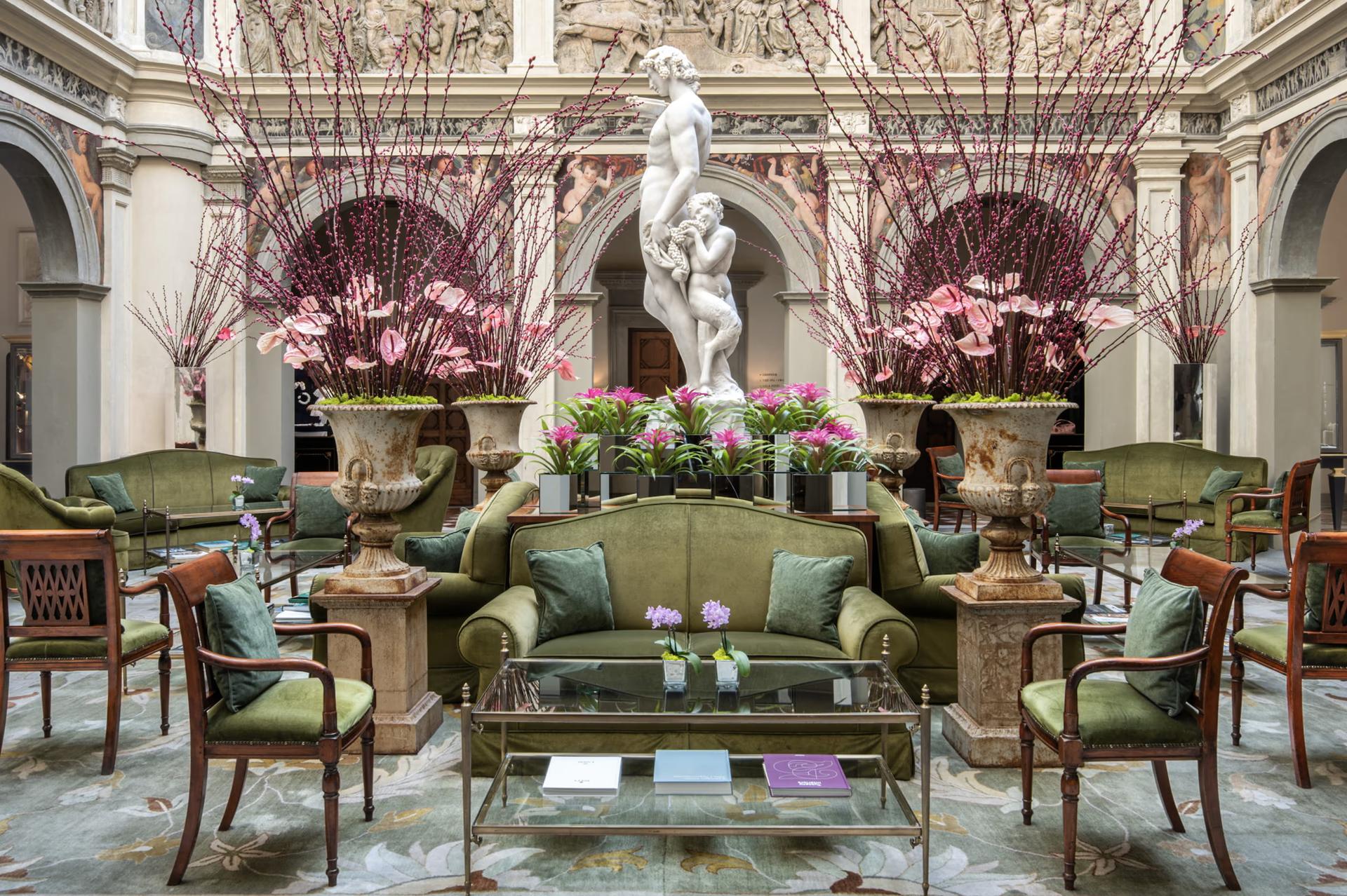 Grand lobby with soaring ceilings, classical frescoes, green upholstered seating, and floral arrangements