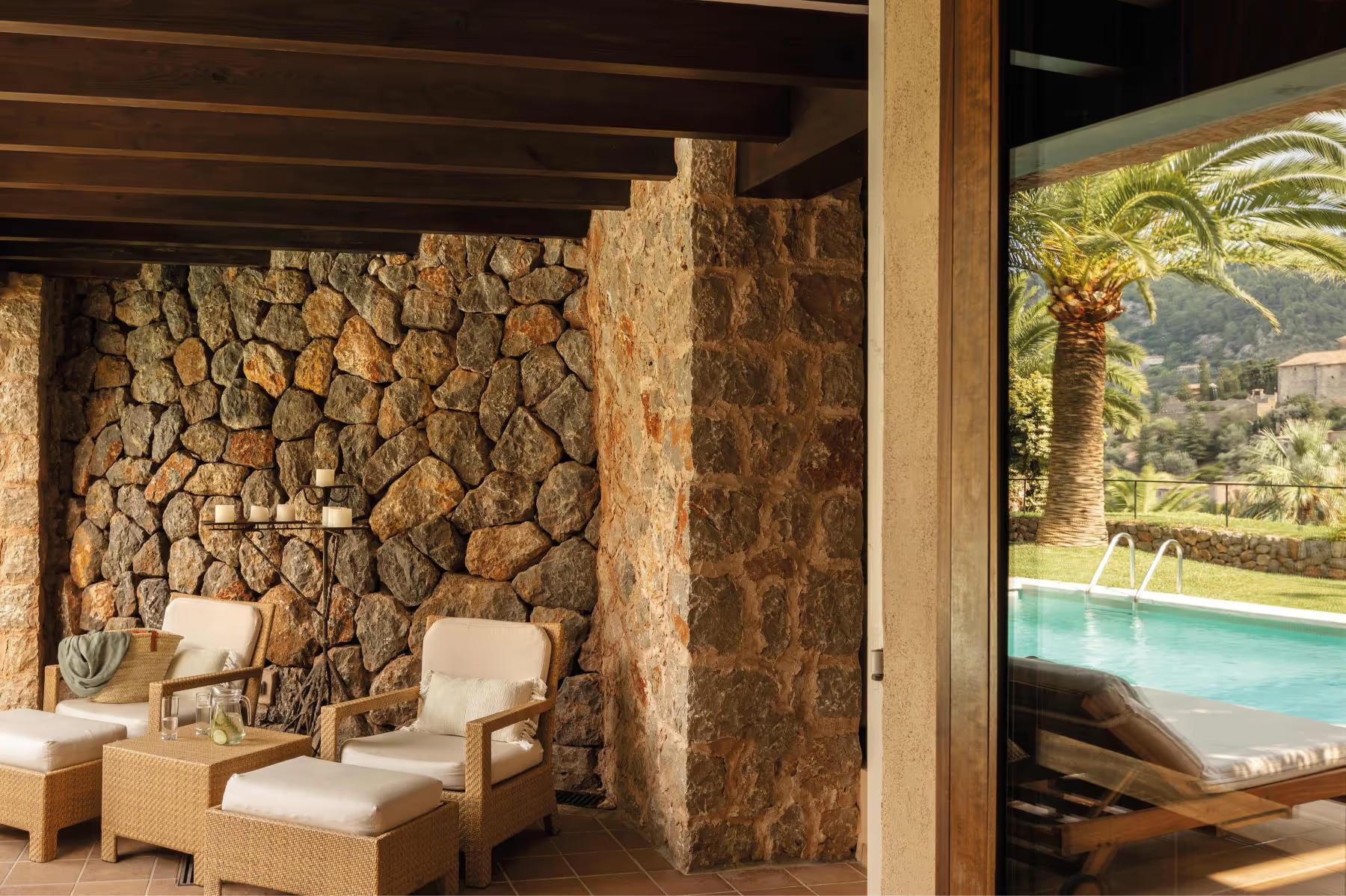 La Residencia: suite alcove with stone walls, cream lounge chairs, wooden ceiling, and pool view