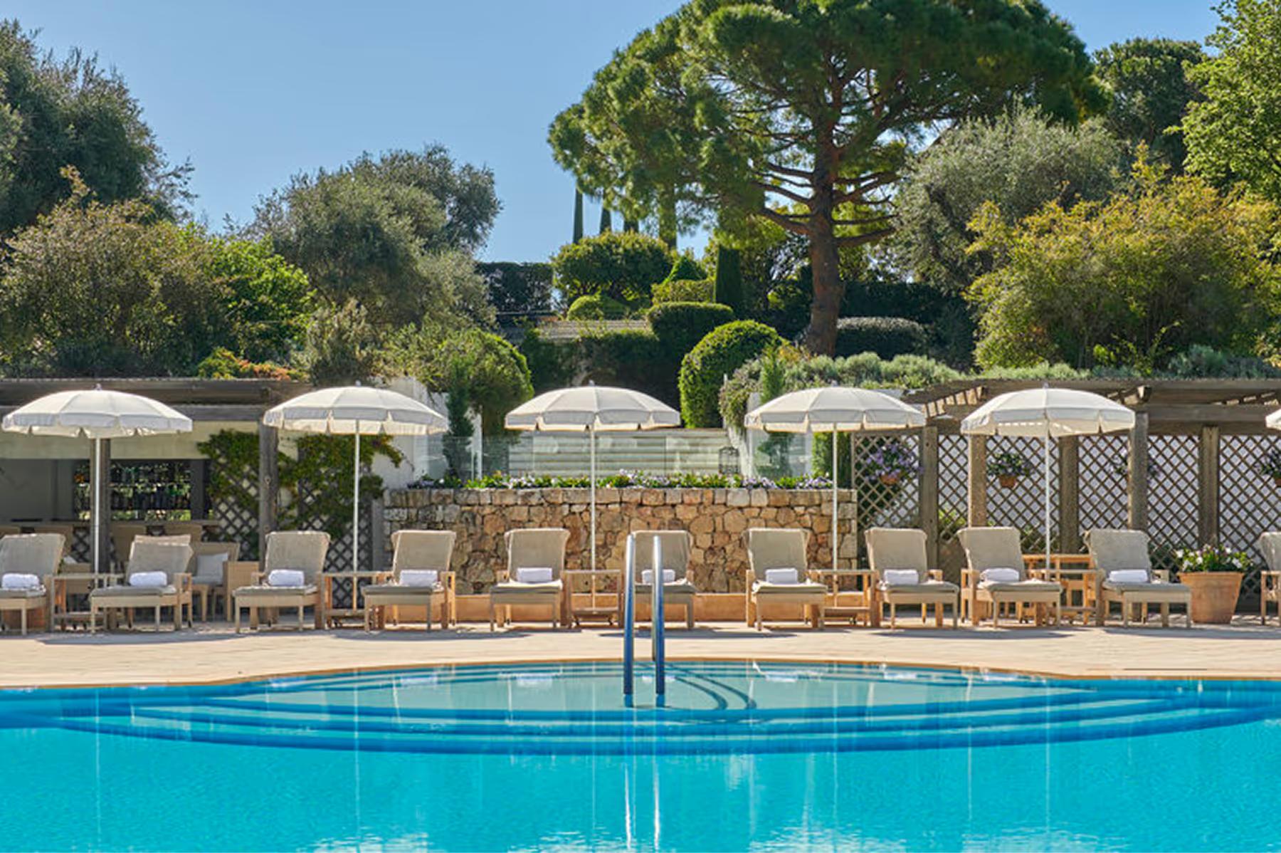 Château Saint Martin & Spa: pool terrace with white umbrellas and lounge chairs in landscaped gardens