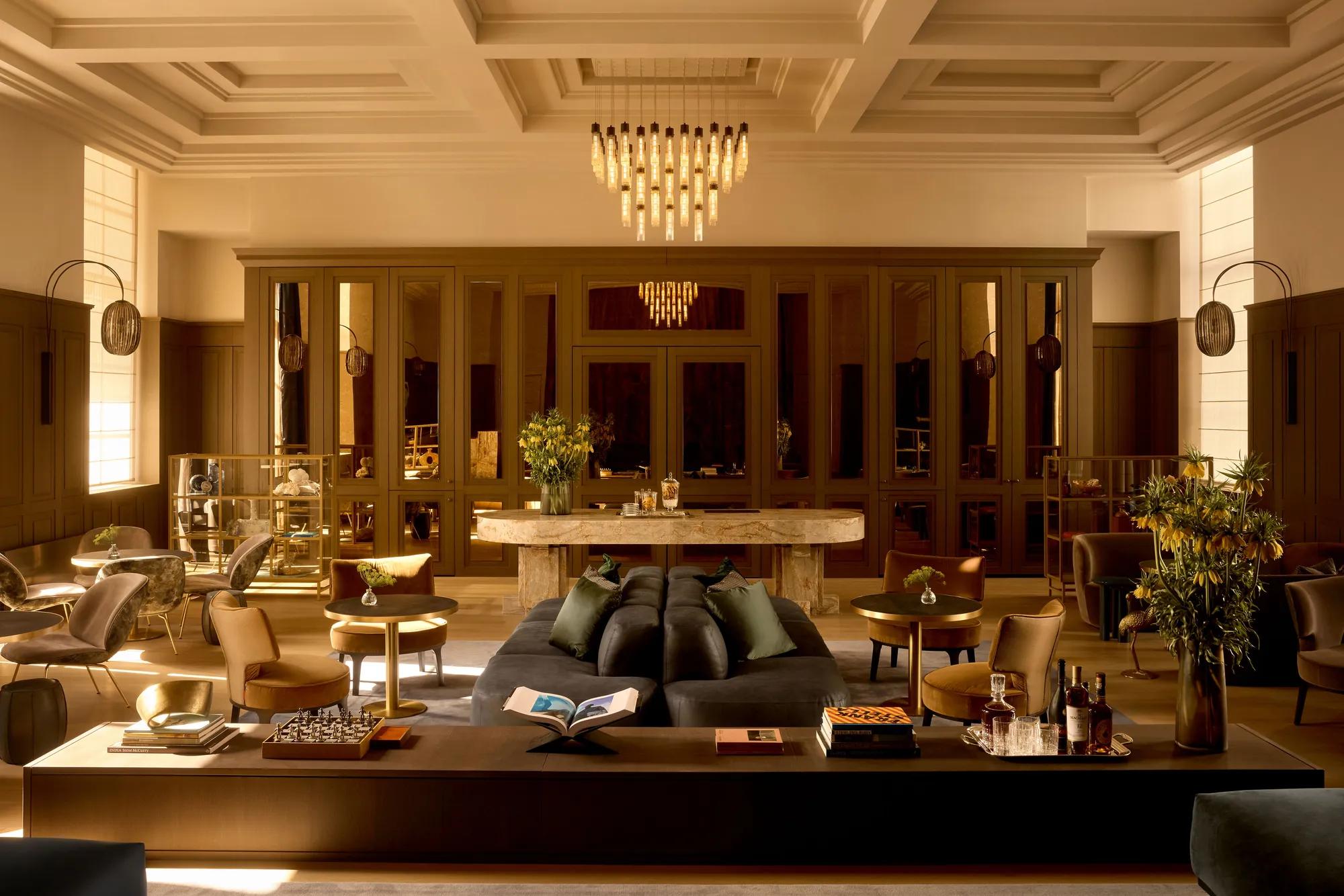 Rosewood Amsterdam: the Grand Library, a former courtroom, with a coffered ceiling, chandelier, and sofas