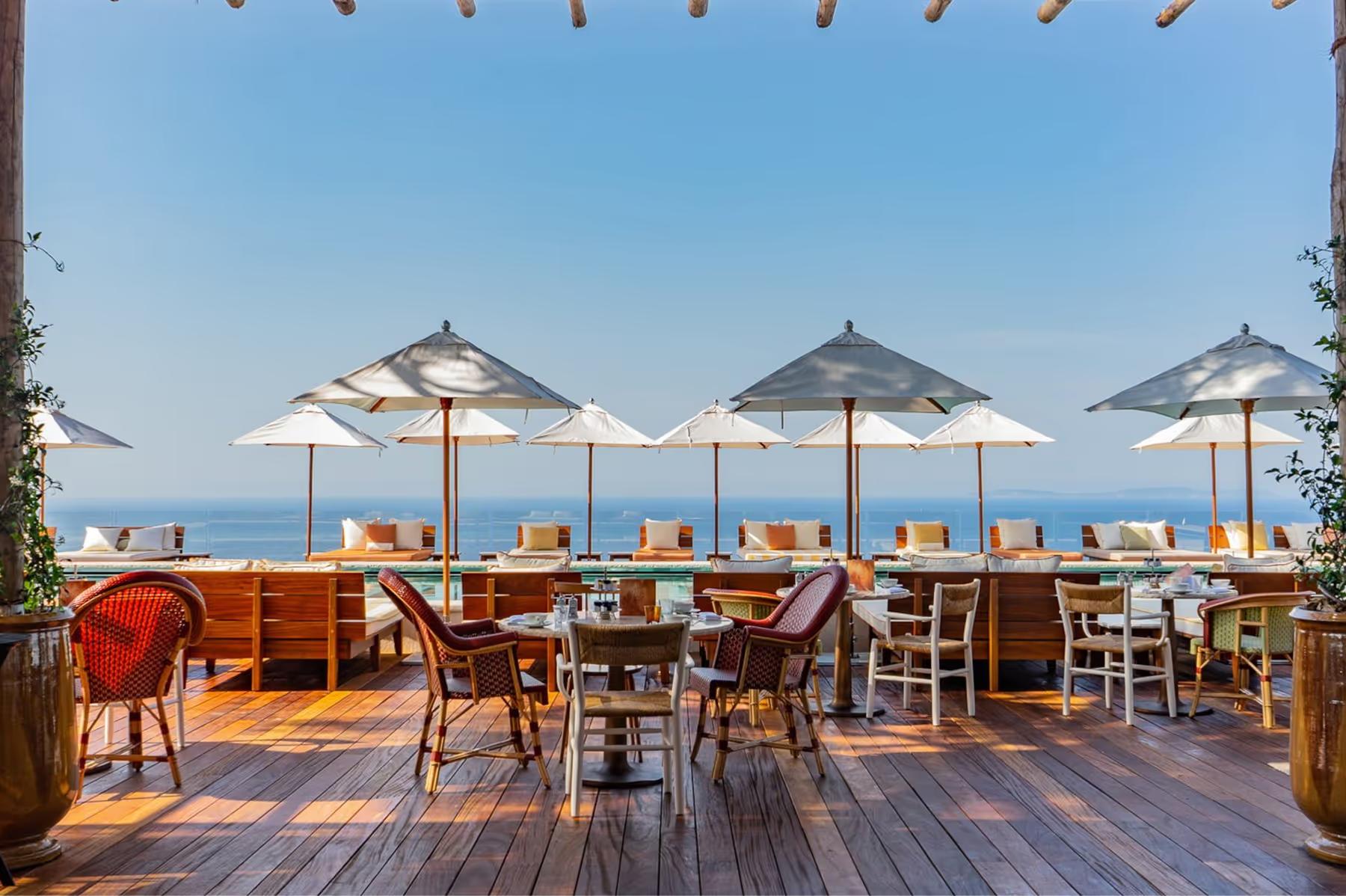 Lily of the Valley: seaside dining deck with striped umbrellas and tables overlooking sea