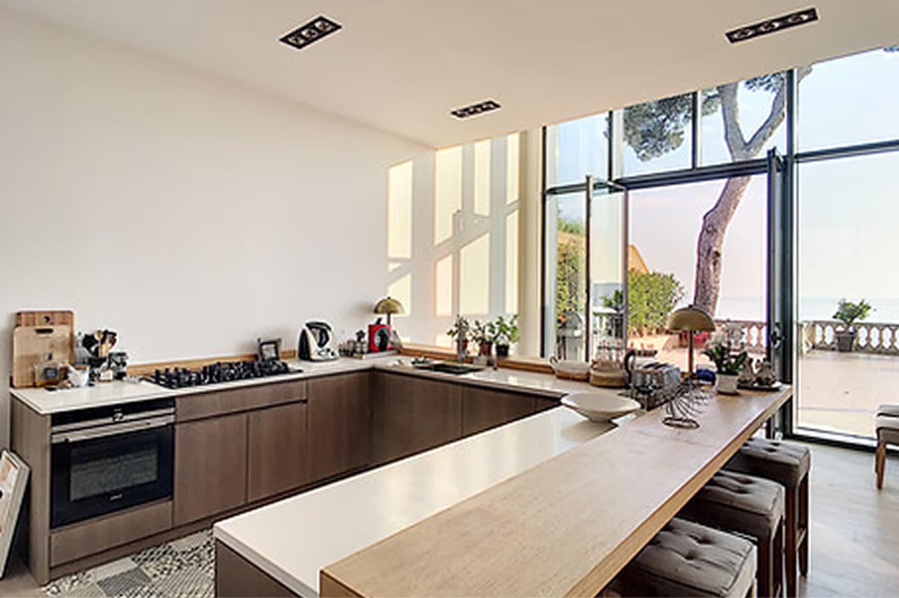 Le Domaine de Canaille: kitchen with stone counters, dark cabinetry, and expansive windows overlooking coastline