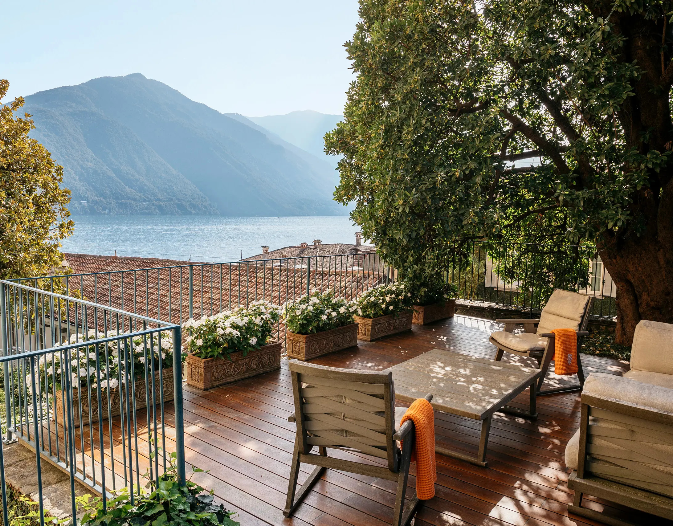 Grand Hotel Tremezzo: rooftop terrace with wooden decking, railing, and forested mountain backdrop