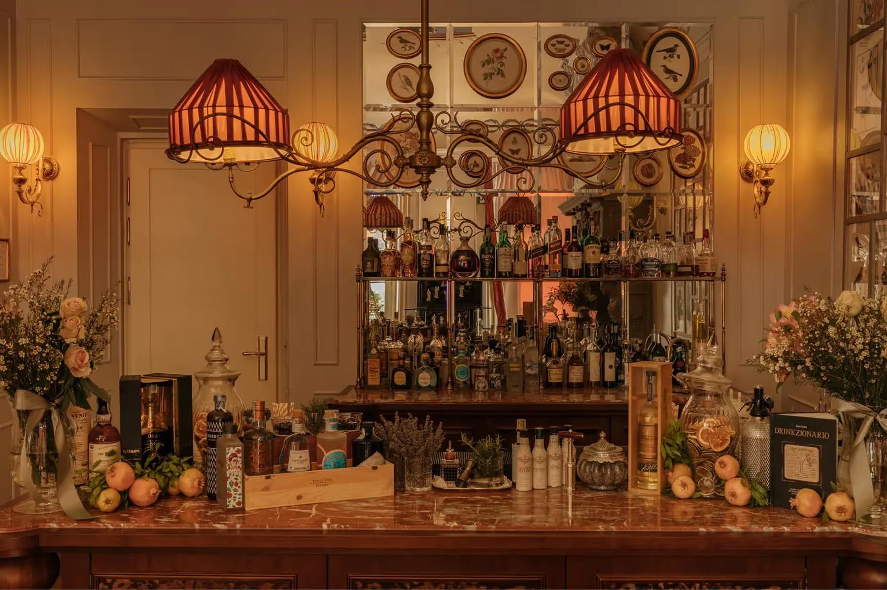 A bar counter with ornate wall plates, stemware, and tiered bottle display