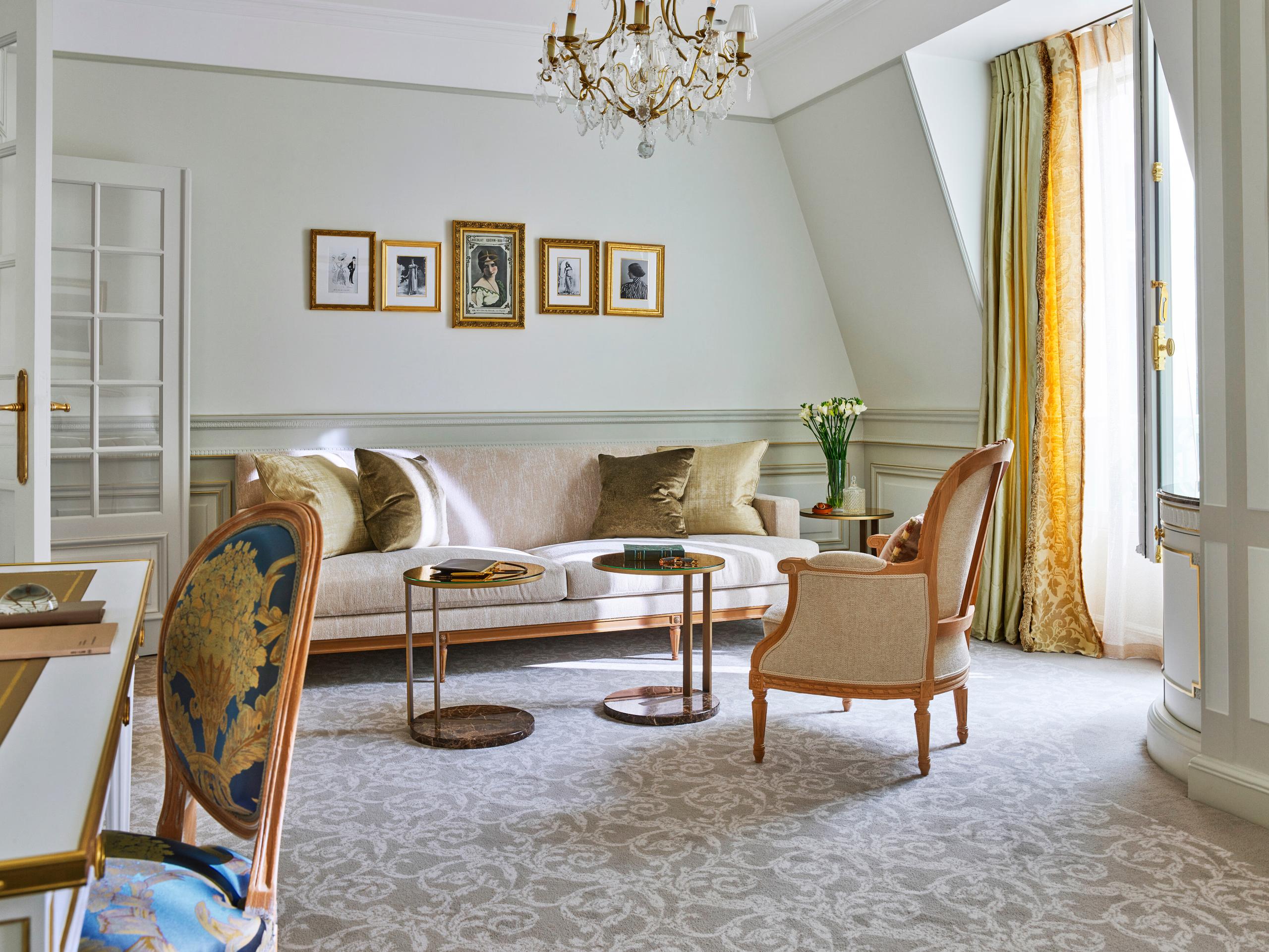Le Meurice: a sitting room in pale tones with sofa, chair, desk, and French doors to a balcony view