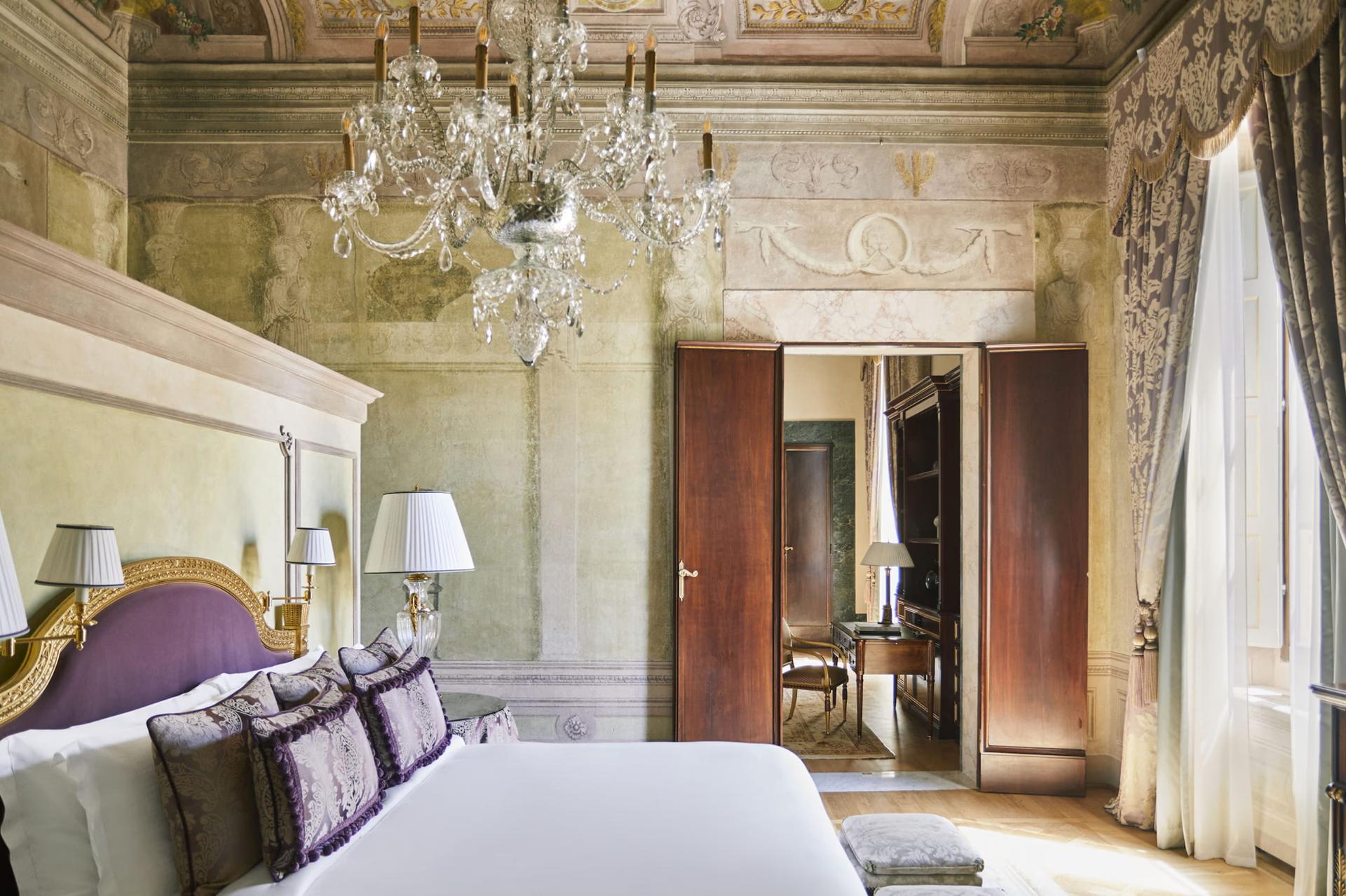 Four Seasons Hotel Firenze: guest room with pale walls, frescoed ceiling, ornate mirror, and double doors opening to adjacent space