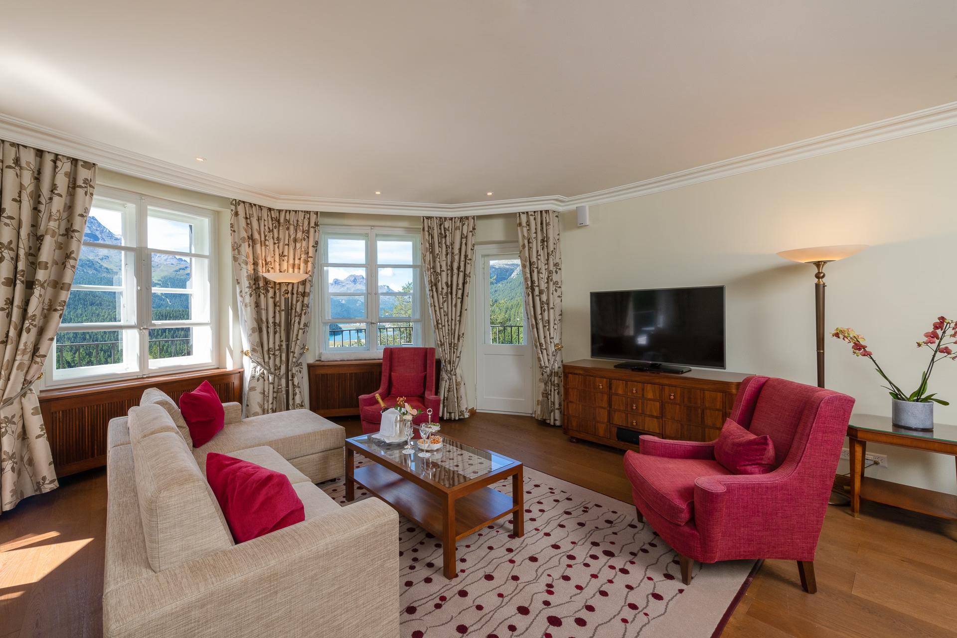 Suvretta House: a suite with sitting area, burgundy accent pieces, bay windows, and traditional furnishings