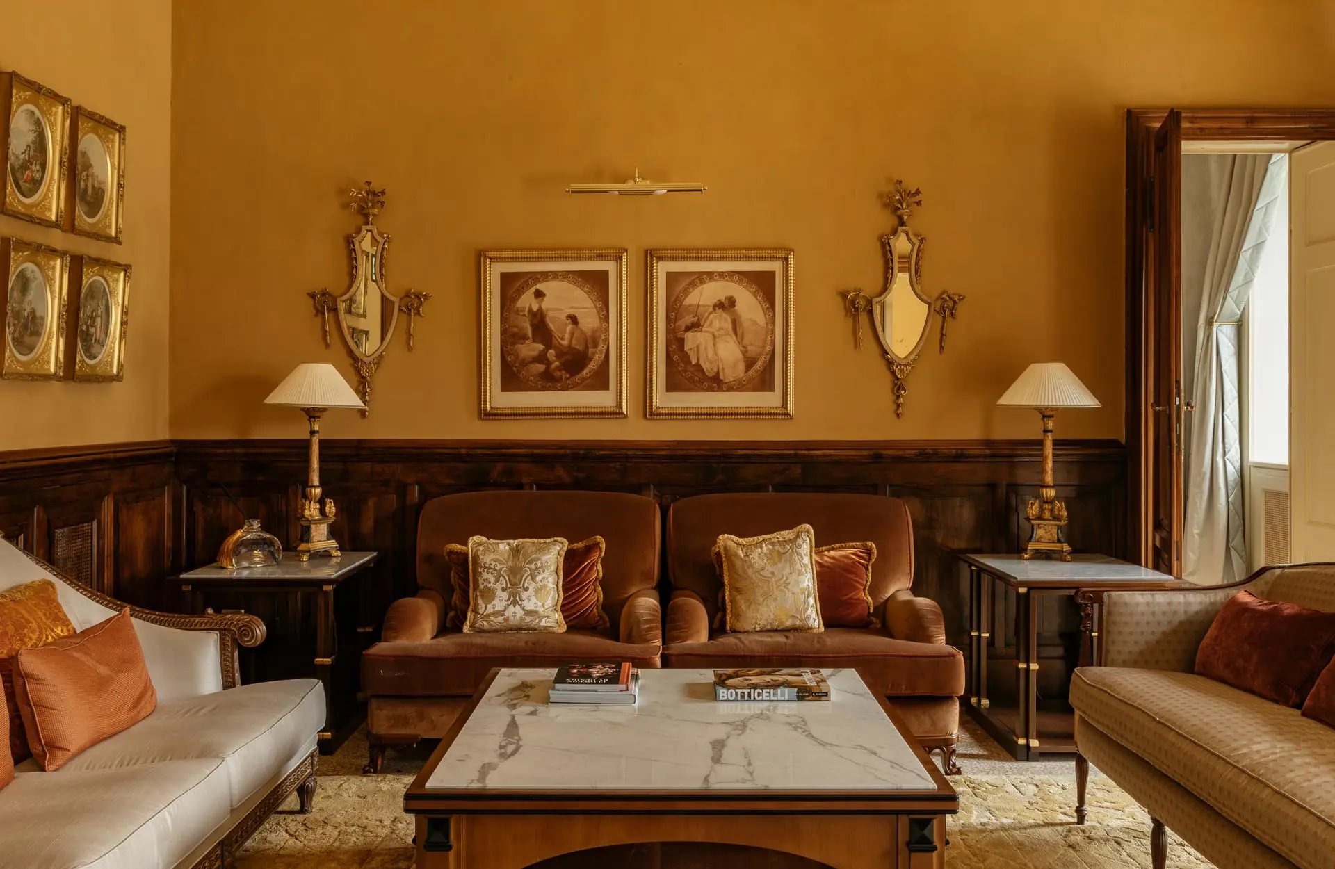 Passalacqua: a salon with amber walls, wood cabinetry, dark leather seating, and gilt details