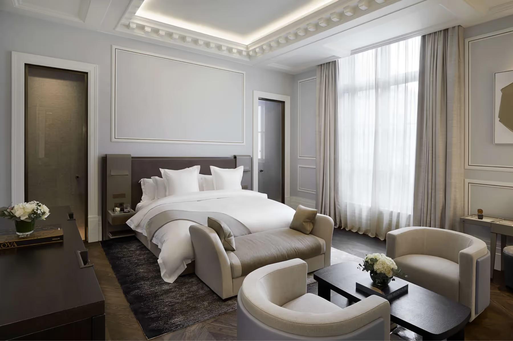 Maison Villeroy: a bedroom with white upholstered headboard, pale furnishings, and two-tone bedside tables