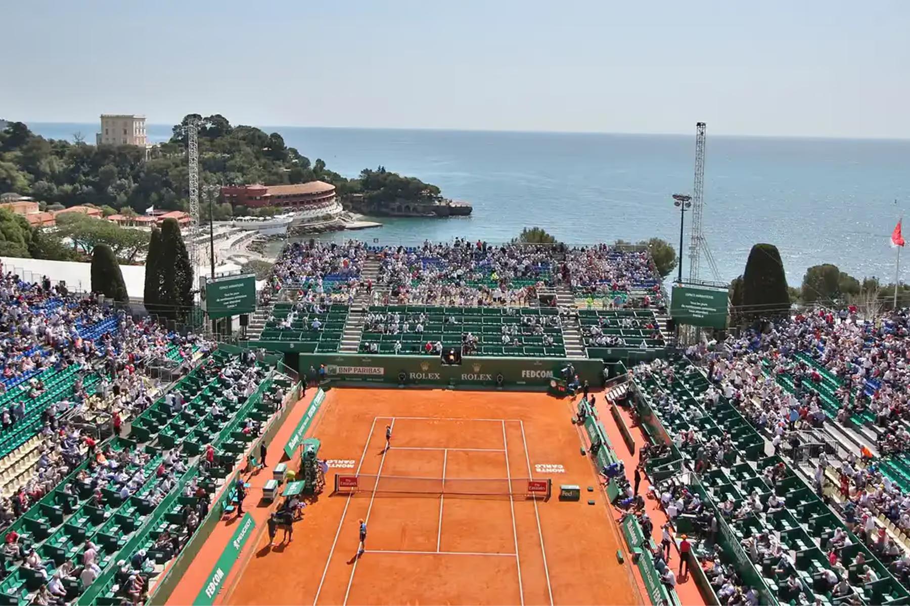 Hôtel Hermitage Monte-Carlo: red clay tennis court with spectator stands overlooking Mediterranean shoreline