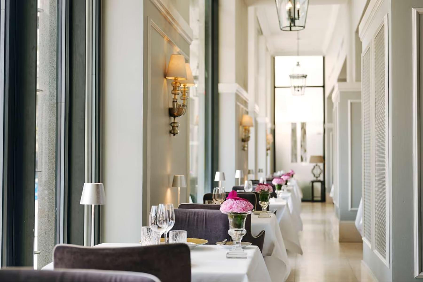 Hotel d’Angleterre: long corridor with mirrors, wall sconces, and set dining tables