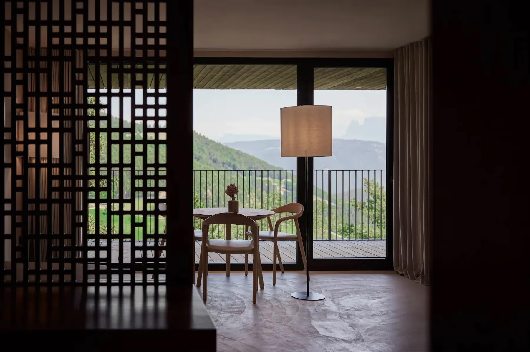 Dining area with geometric wooden screen partition and mountain view through glass doors