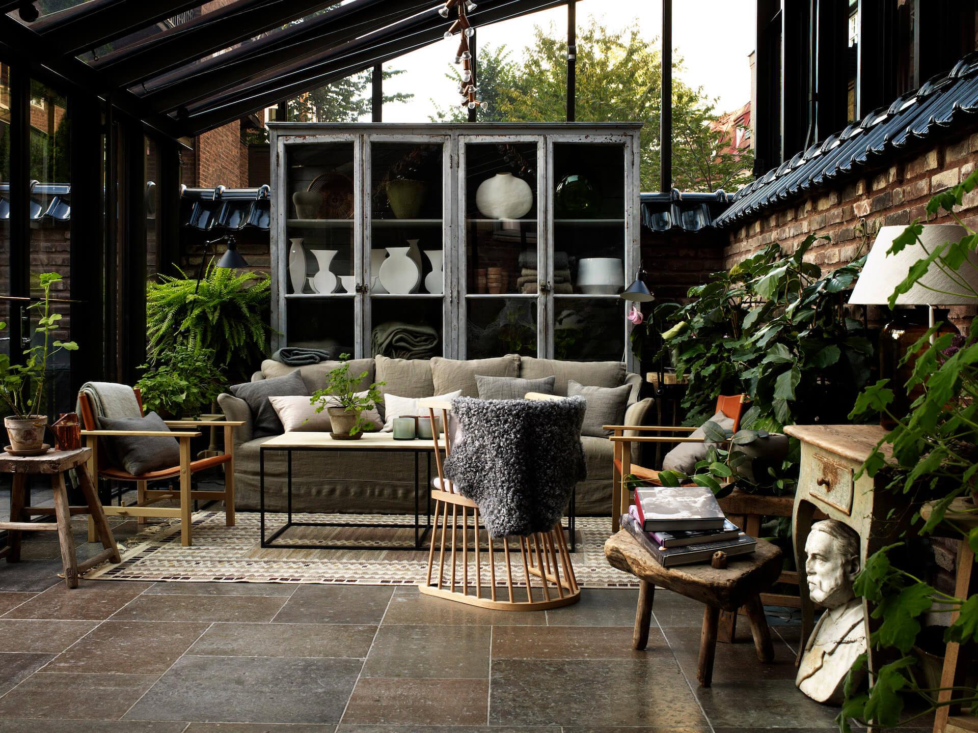 Ett Hem: a covered terrace with wooden and rattan furniture, skylights, and potted plants