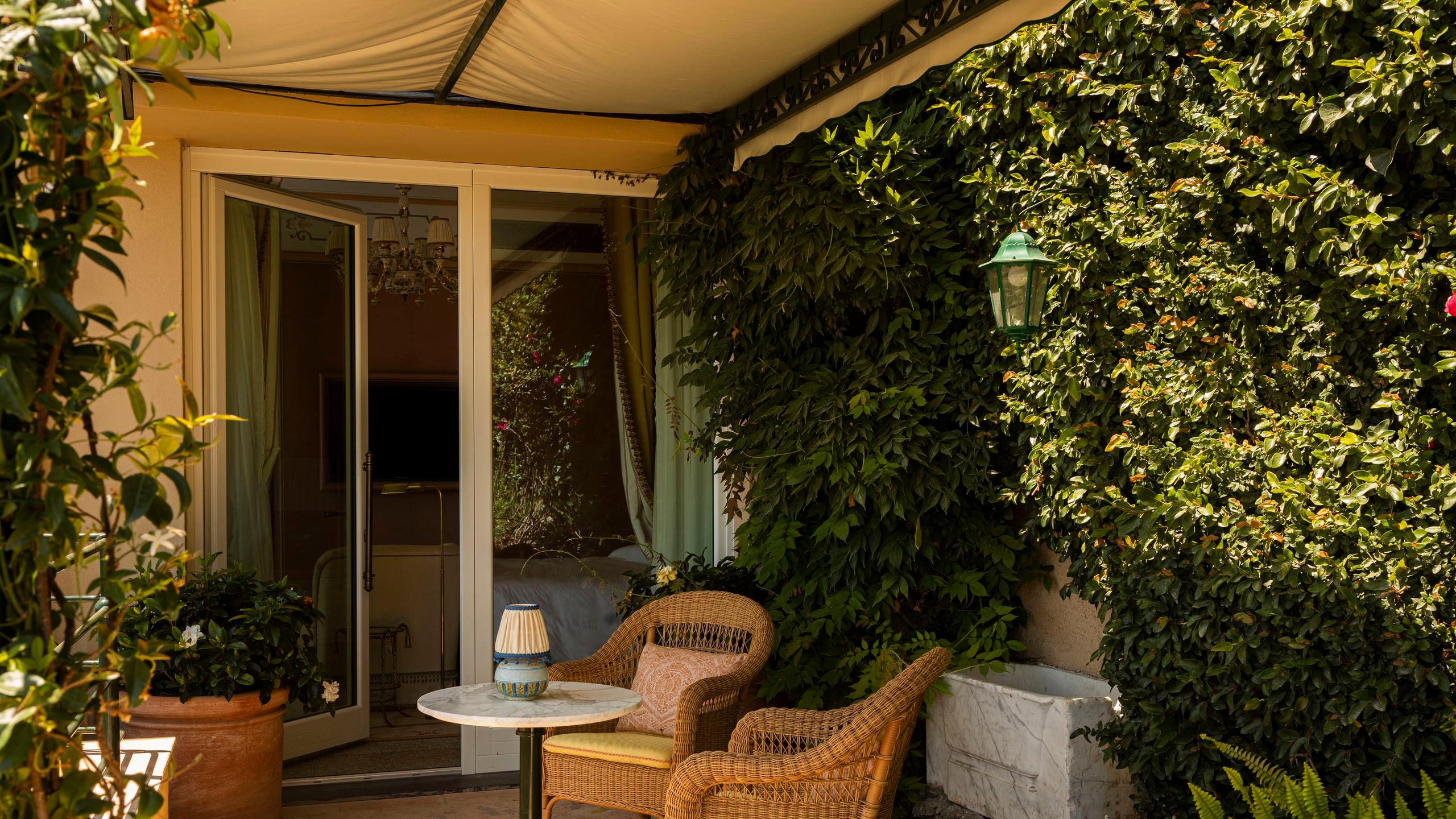 A covered outdoor terrace with lounge chair and hillside ocean view