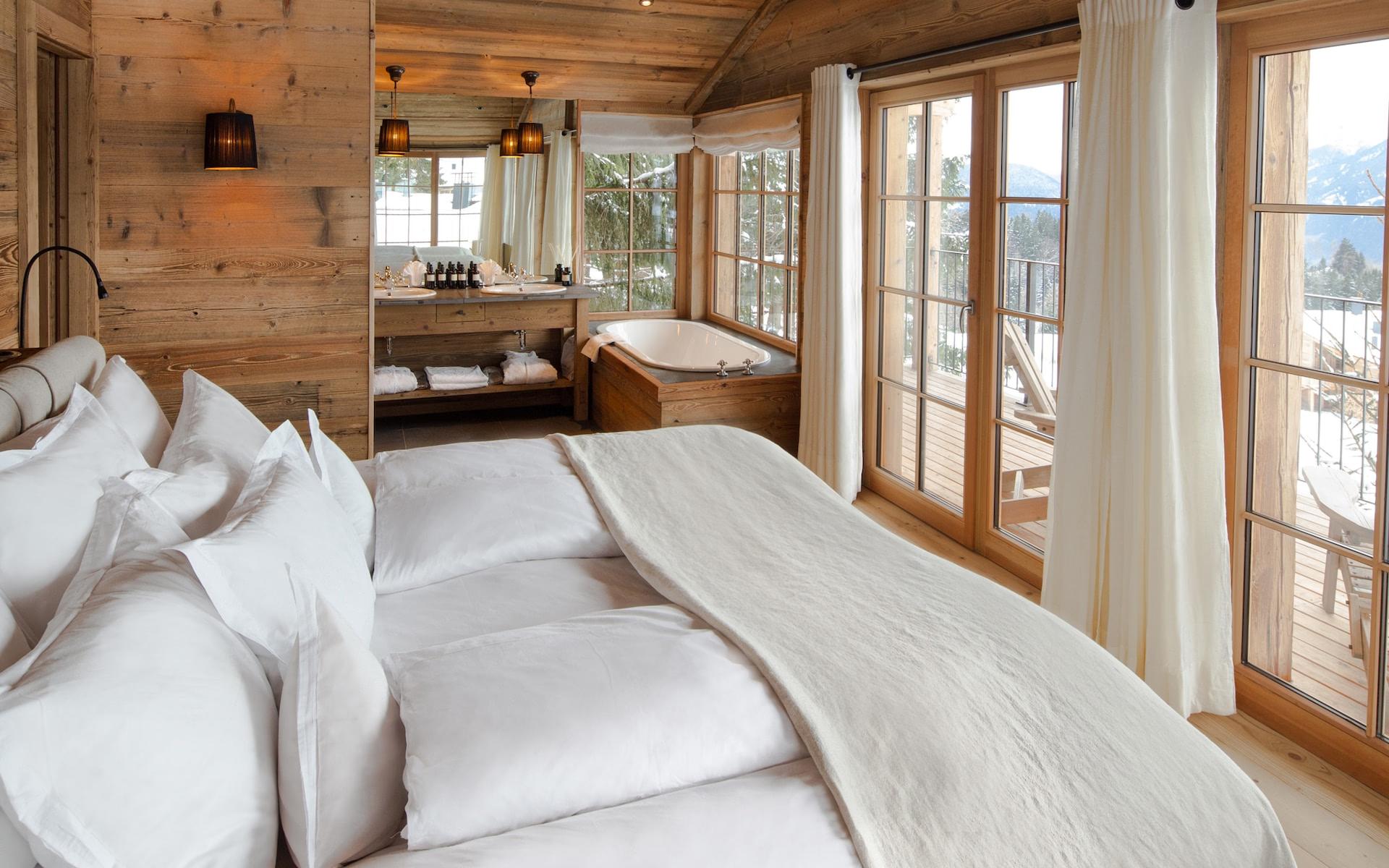 Wooden bedroom with white bedding and glass doors opening to a terrace