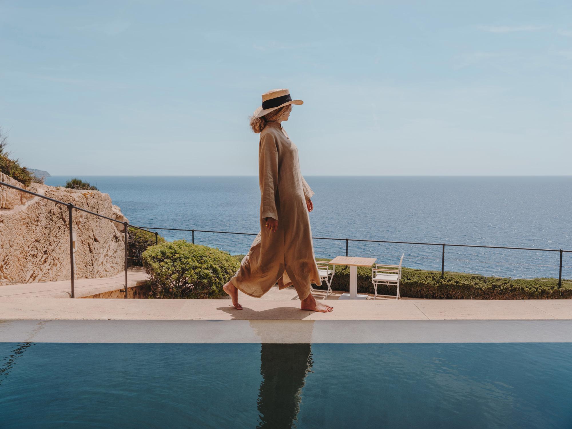 Cap Rocat: a sailboat and turquoise waters below a coastal terrace railing, at golden hour