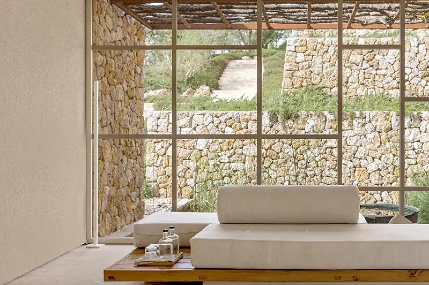 Wellness room with window seating alcove, layered stone wall, and minimalist furnishings