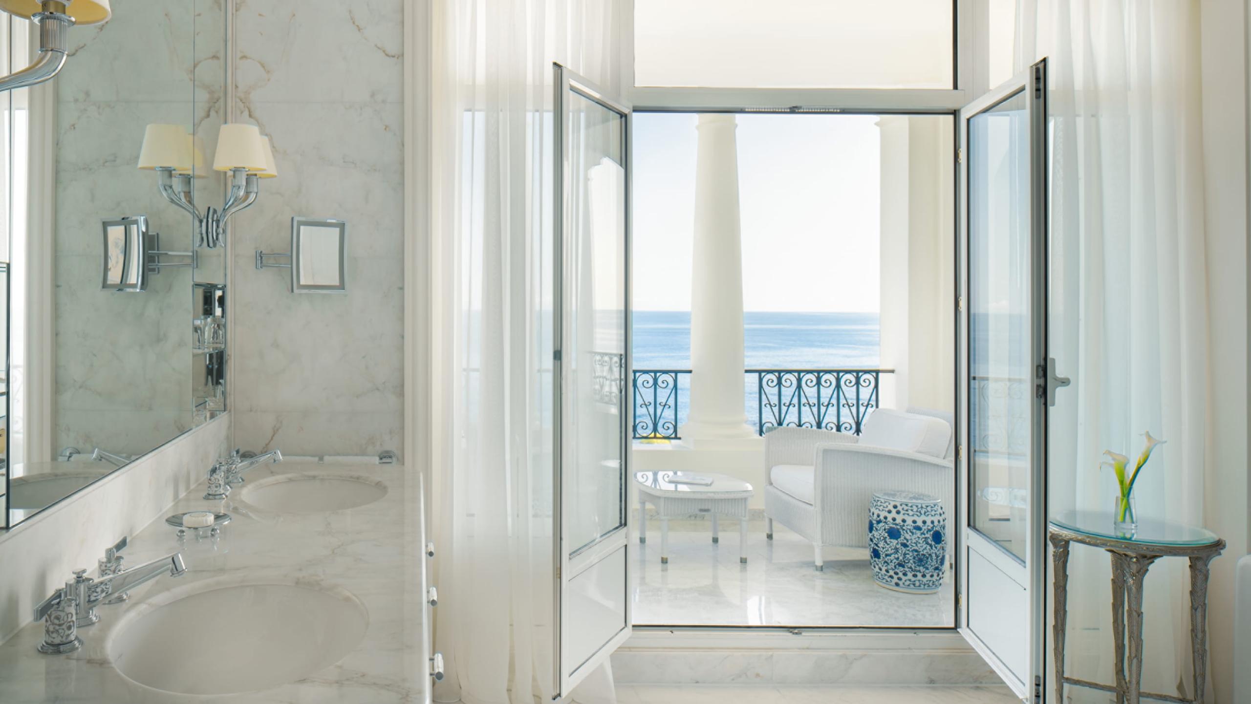 Spa-like marble bathroom with a soaking tub and sea view through glass doors