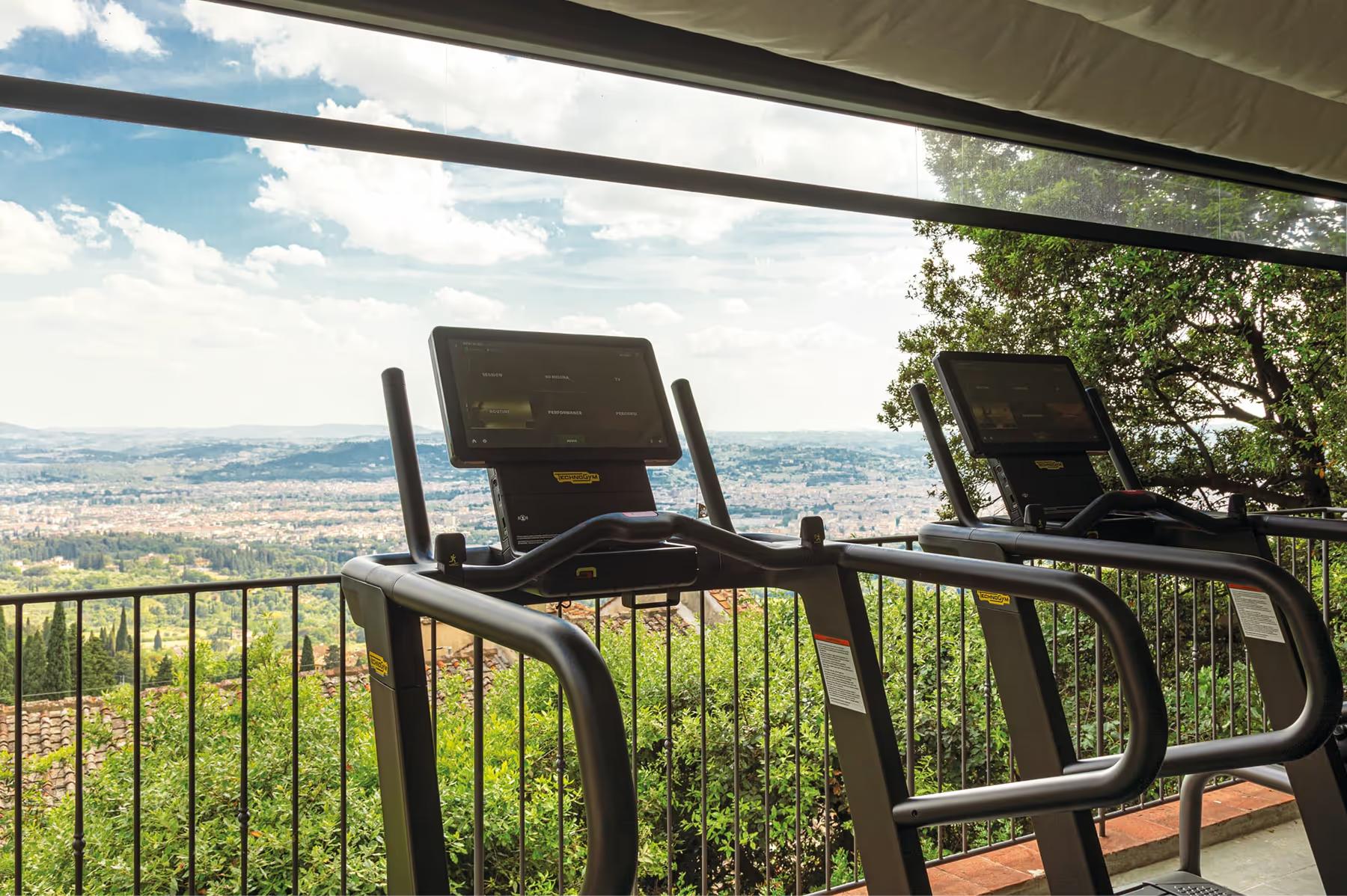 Exercise equipment on a terrace overlooking the Tuscany landscape with protective railings