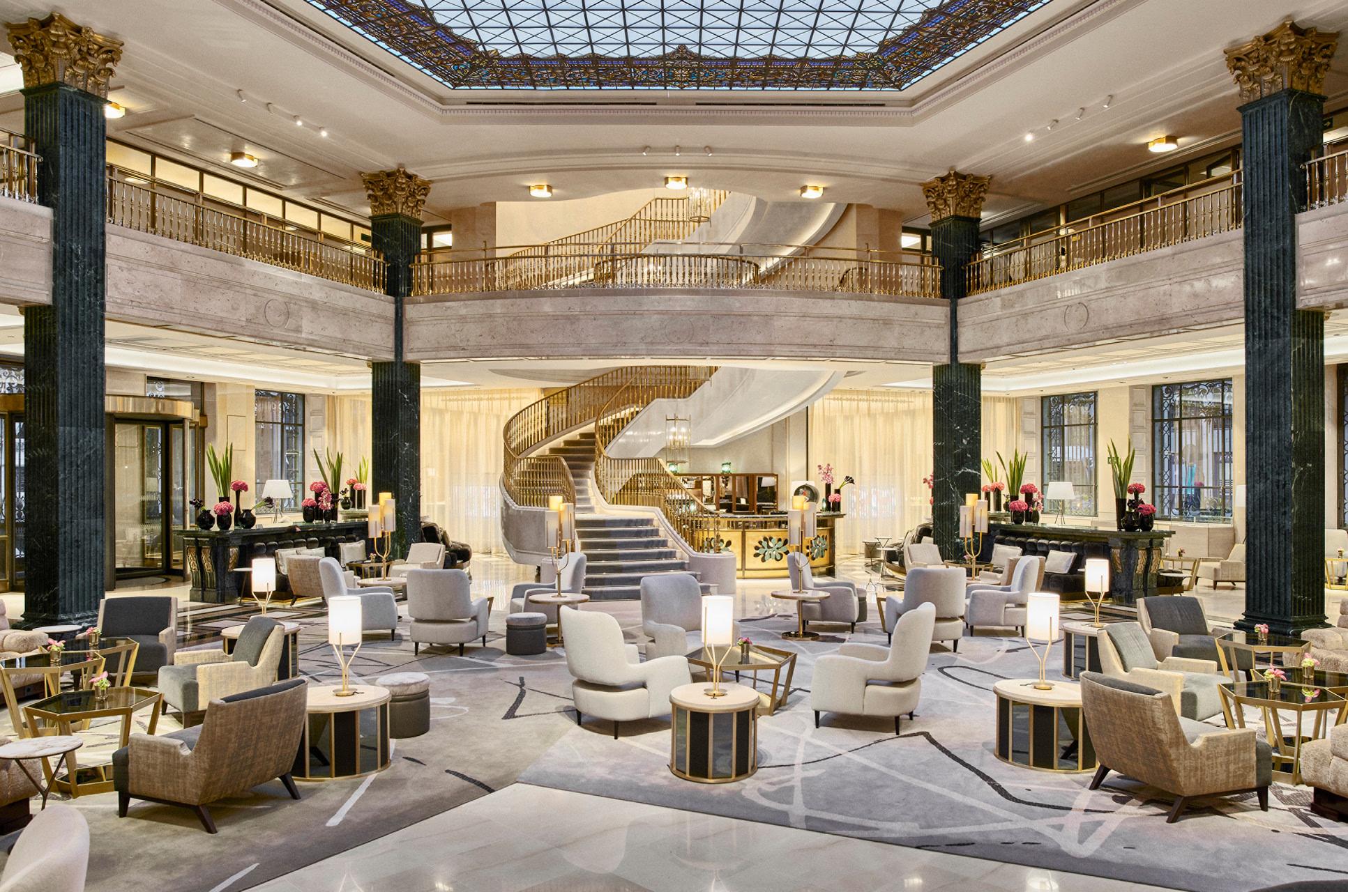 Grand lobby with columns, coffered ceiling, neutral seating arrangements, and skylight above