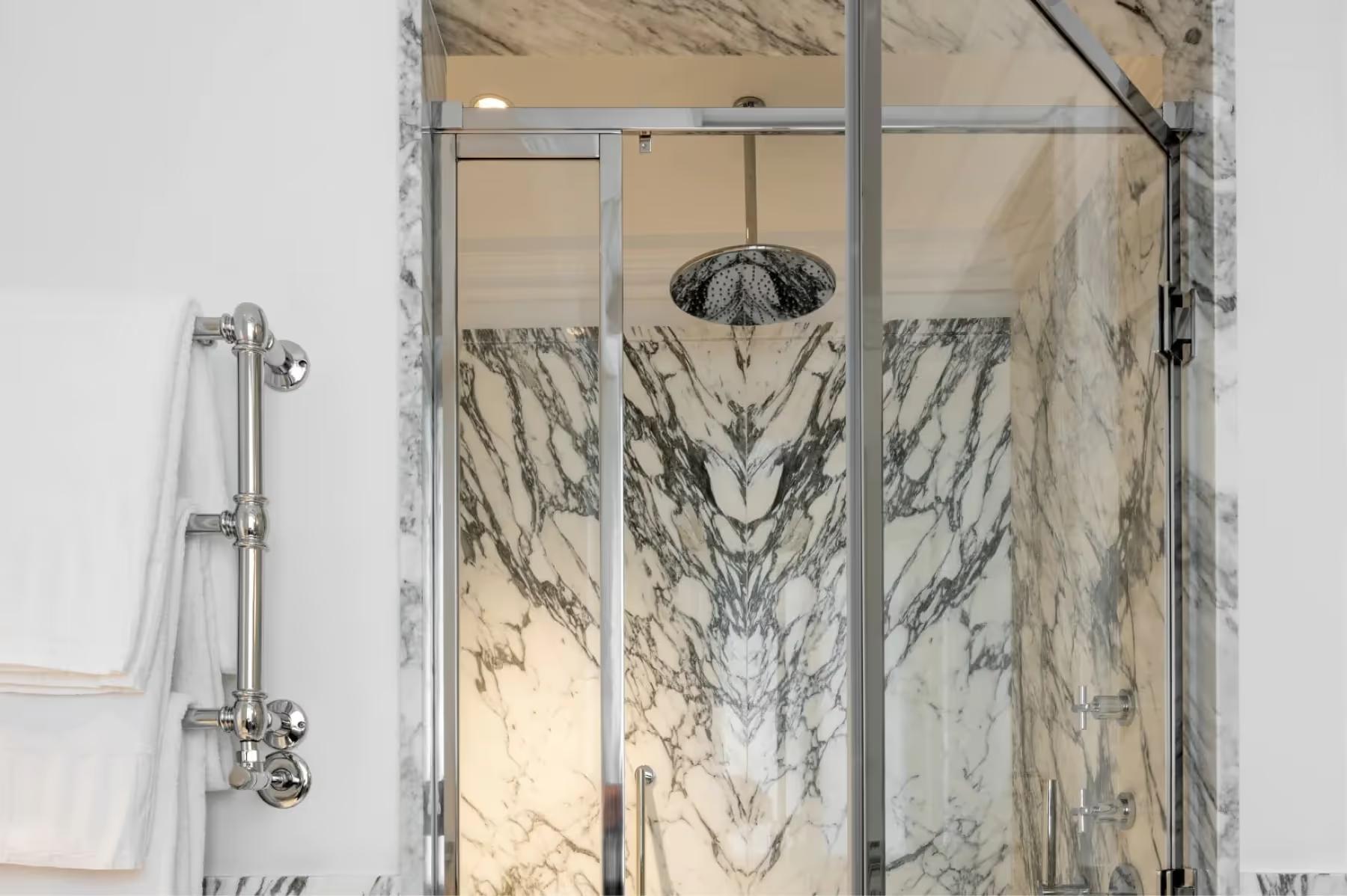 Glass shower enclosure with marble walls and rain showerhead