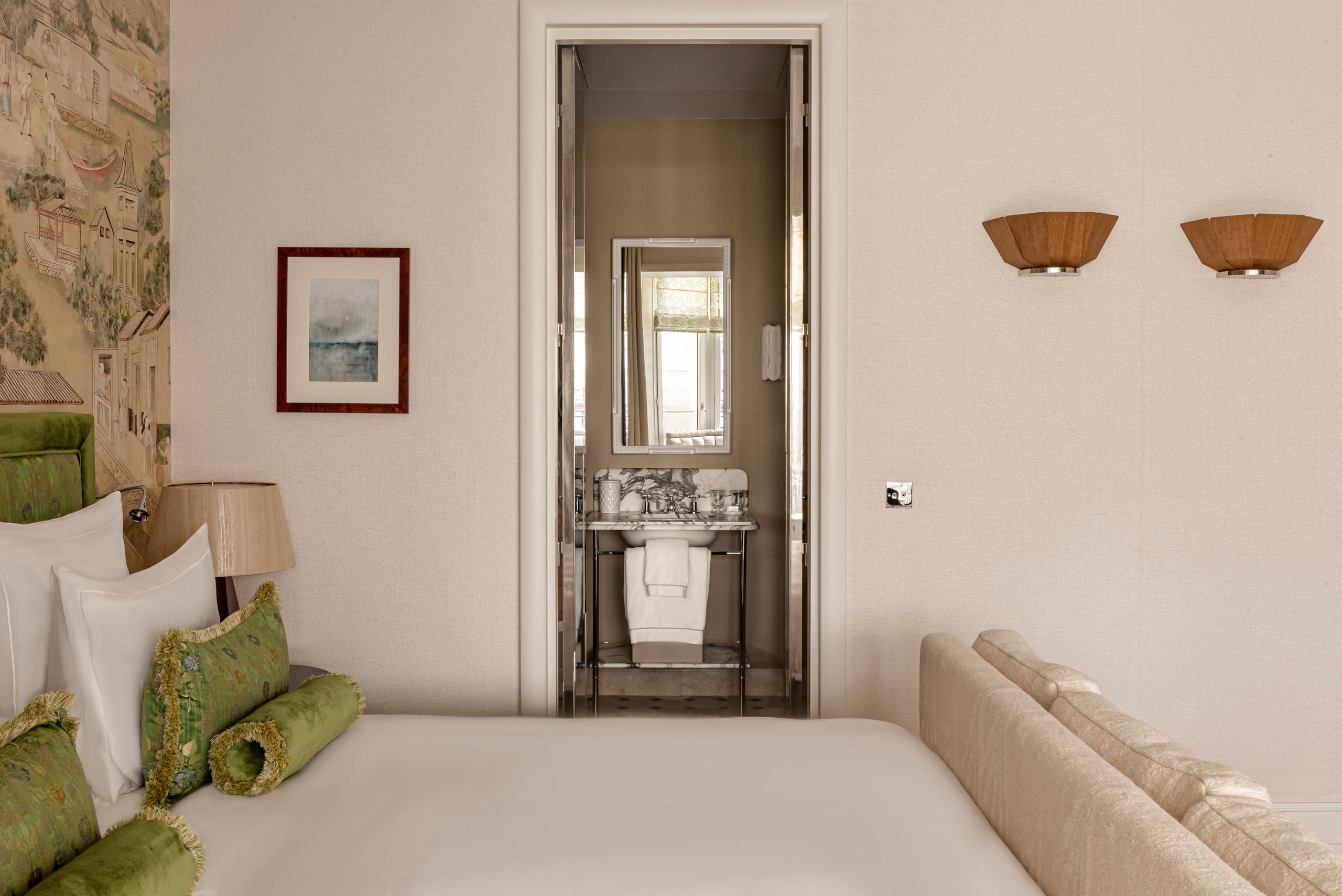 Suite interior with vintage furniture, wall-mounted mirror above desk, and garden access