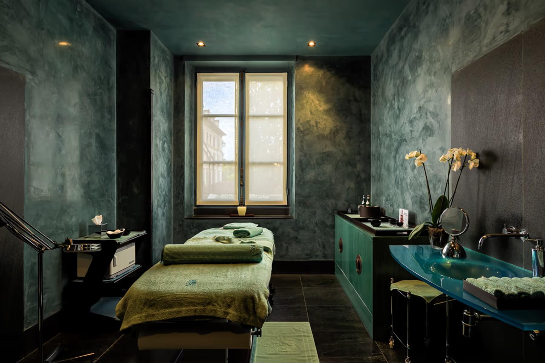 Villa d’Este: spa treatment room with calming blue-green aesthetic and single massage bed