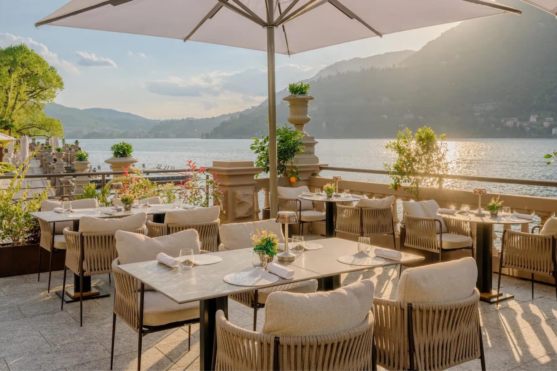 Mandarin Oriental, Lake Como: covered terrace with round tables and chairs positioned along waterfront with mountains beyond