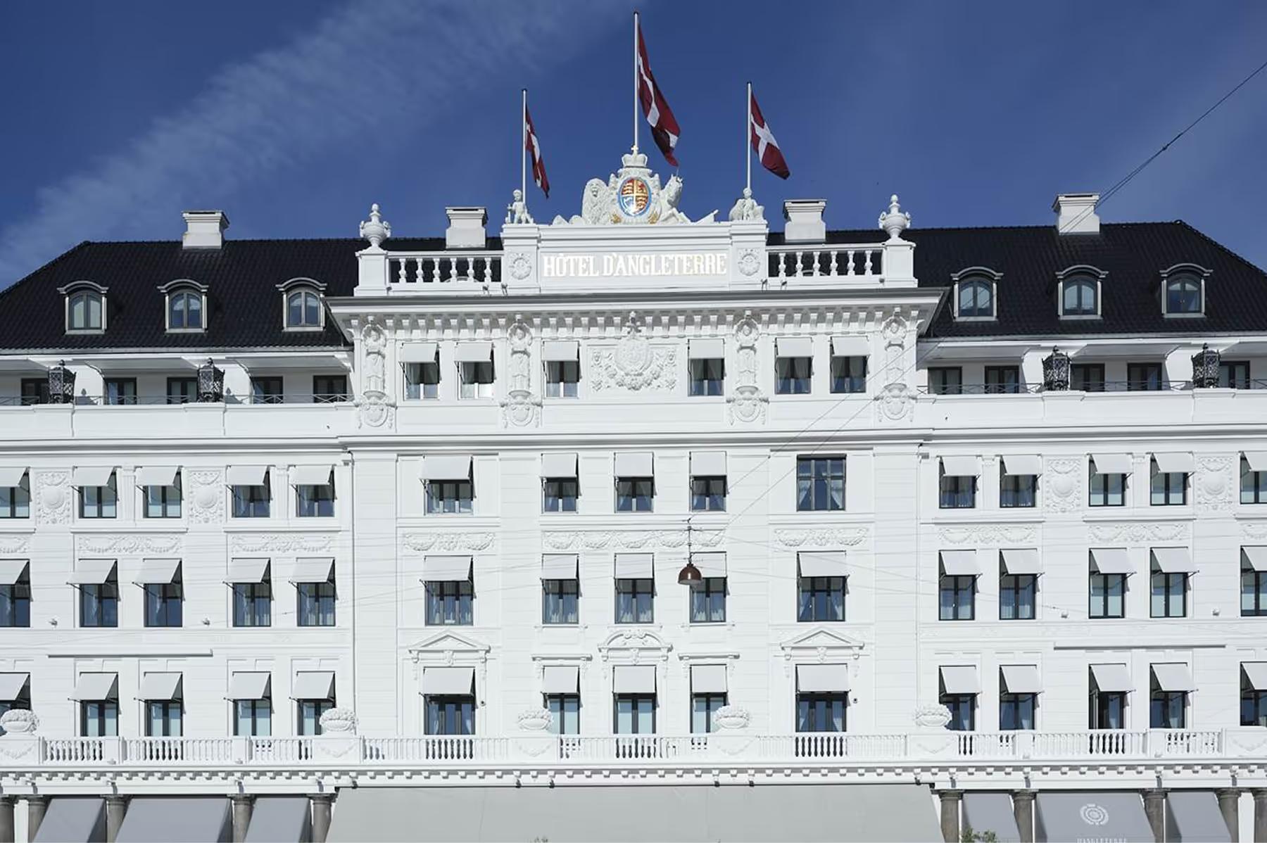 Pale facade with mansard roof and royal flags at Kongens Nytorv