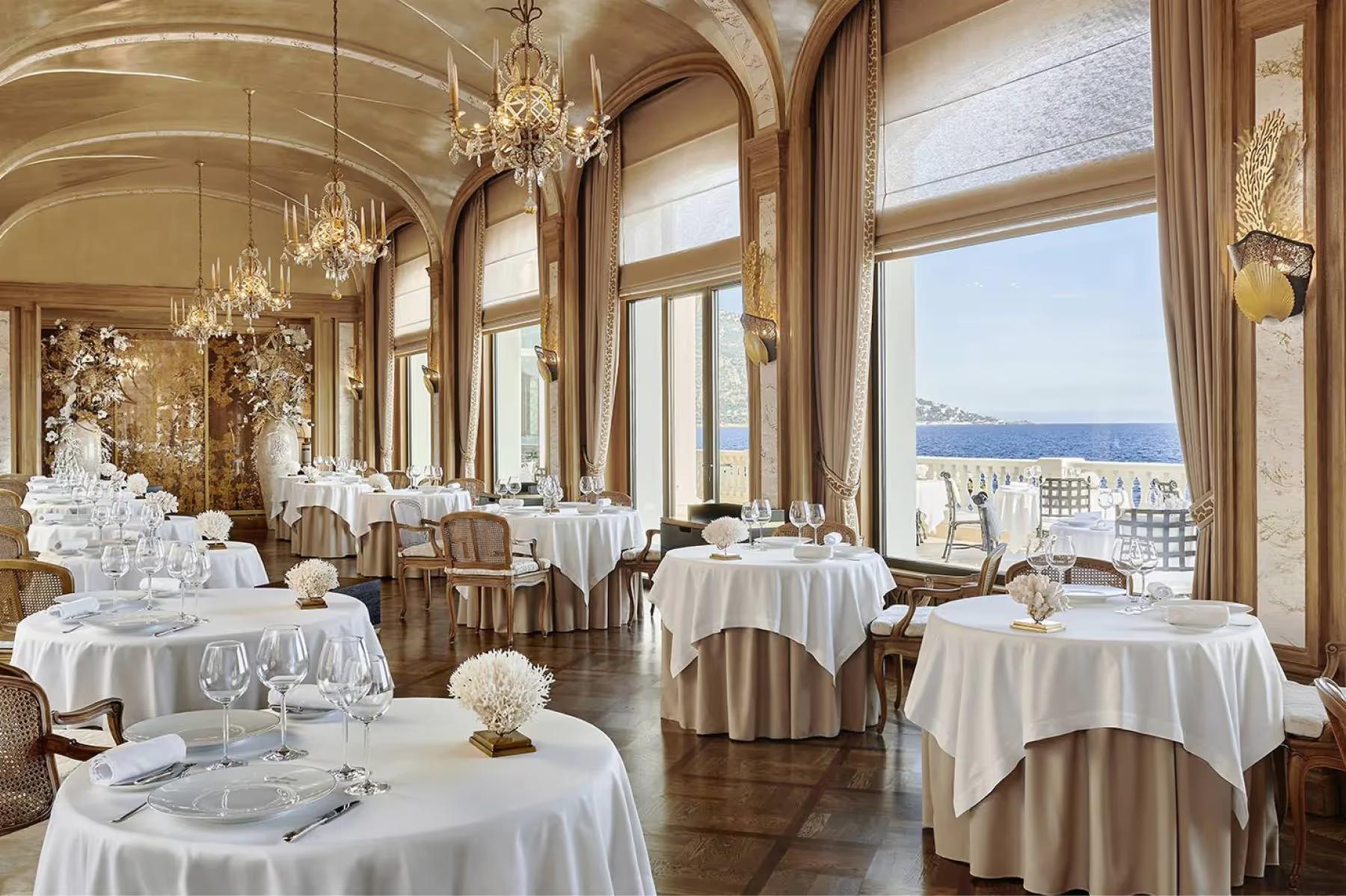 La Réserve de Beaulieu: formal dining room with arched windows, crystal chandeliers, and sea views