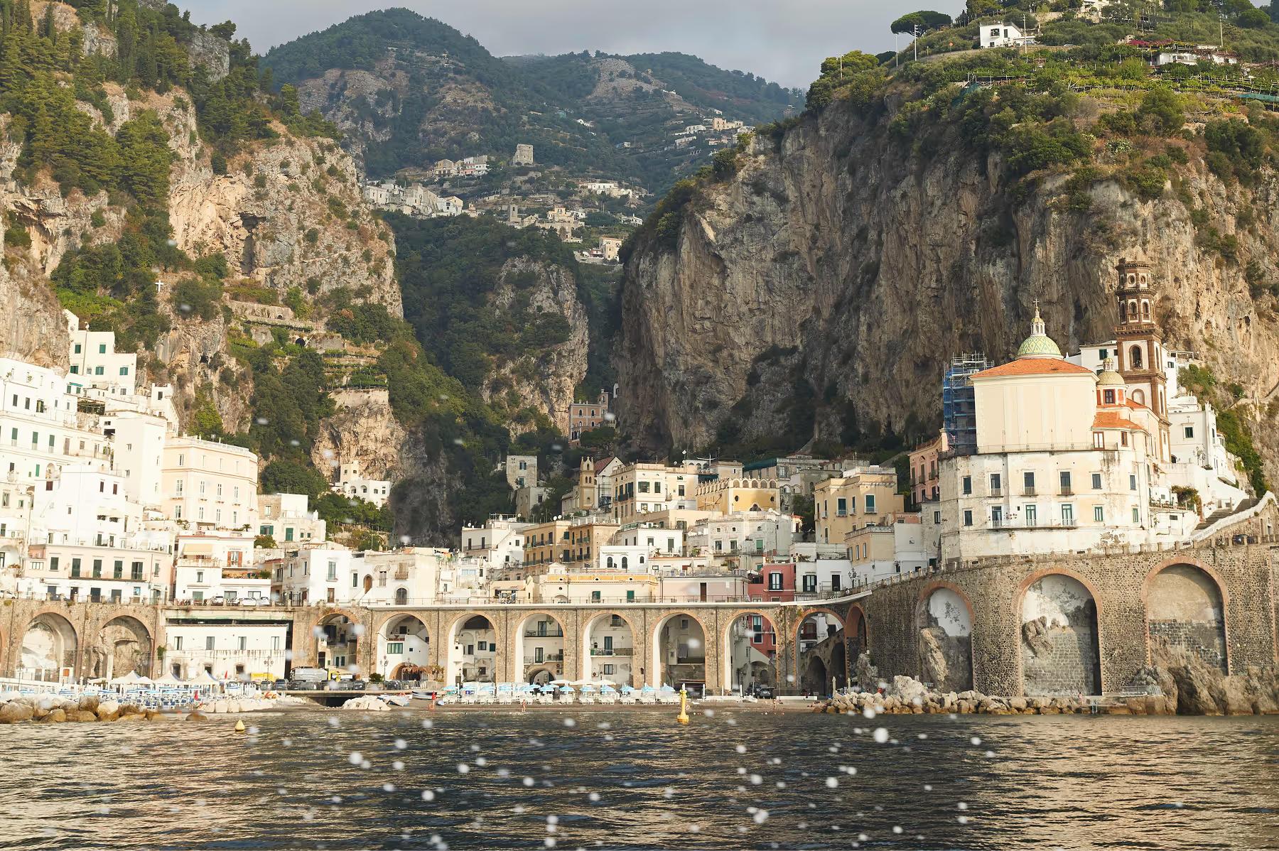 Caruso: waterfront village set in cliffs with colorful buildings, harbor boats, and mountain backdrop