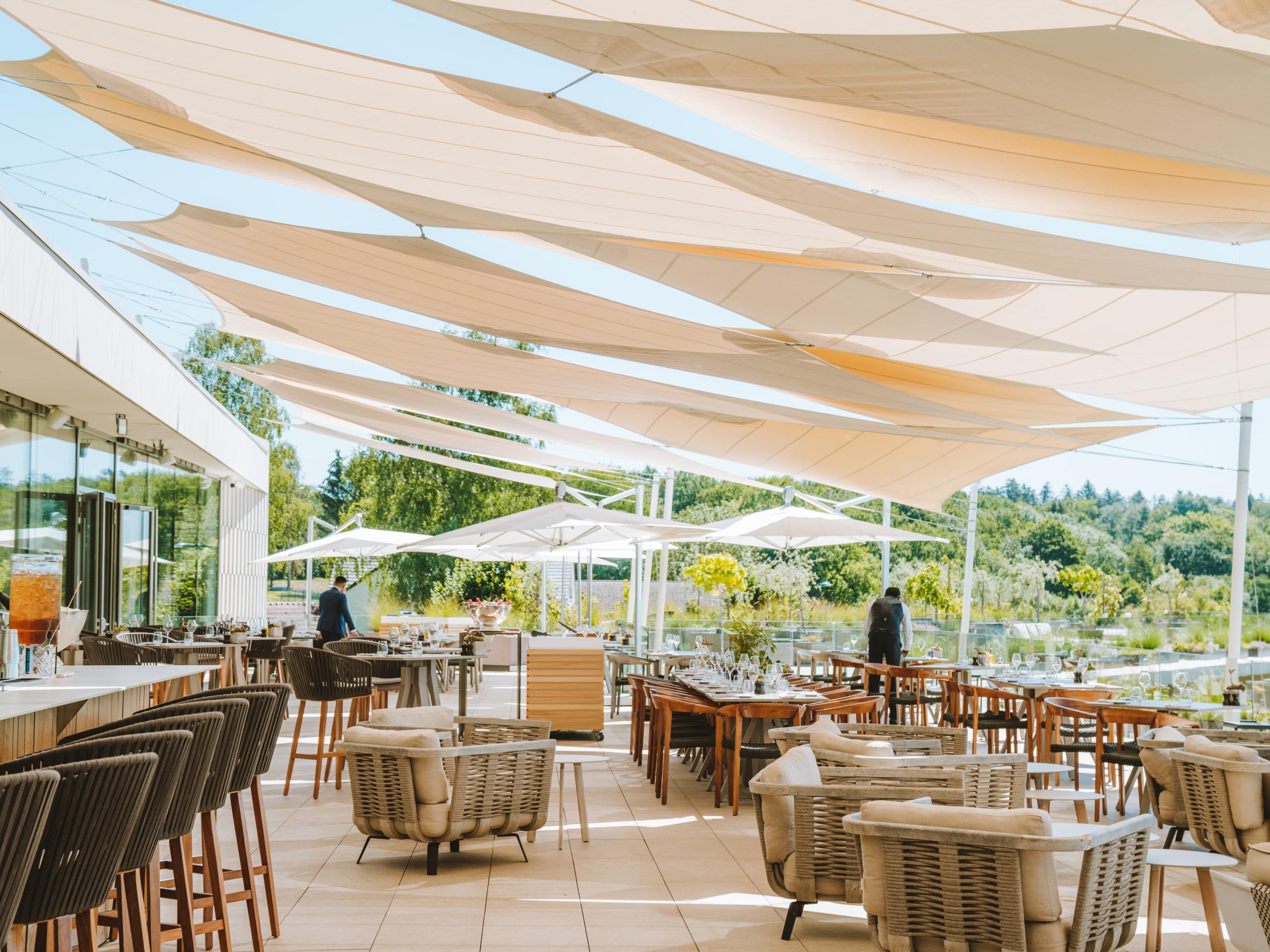 Casual outdoor terrace with striped shade canopies and furniture with vineyard views