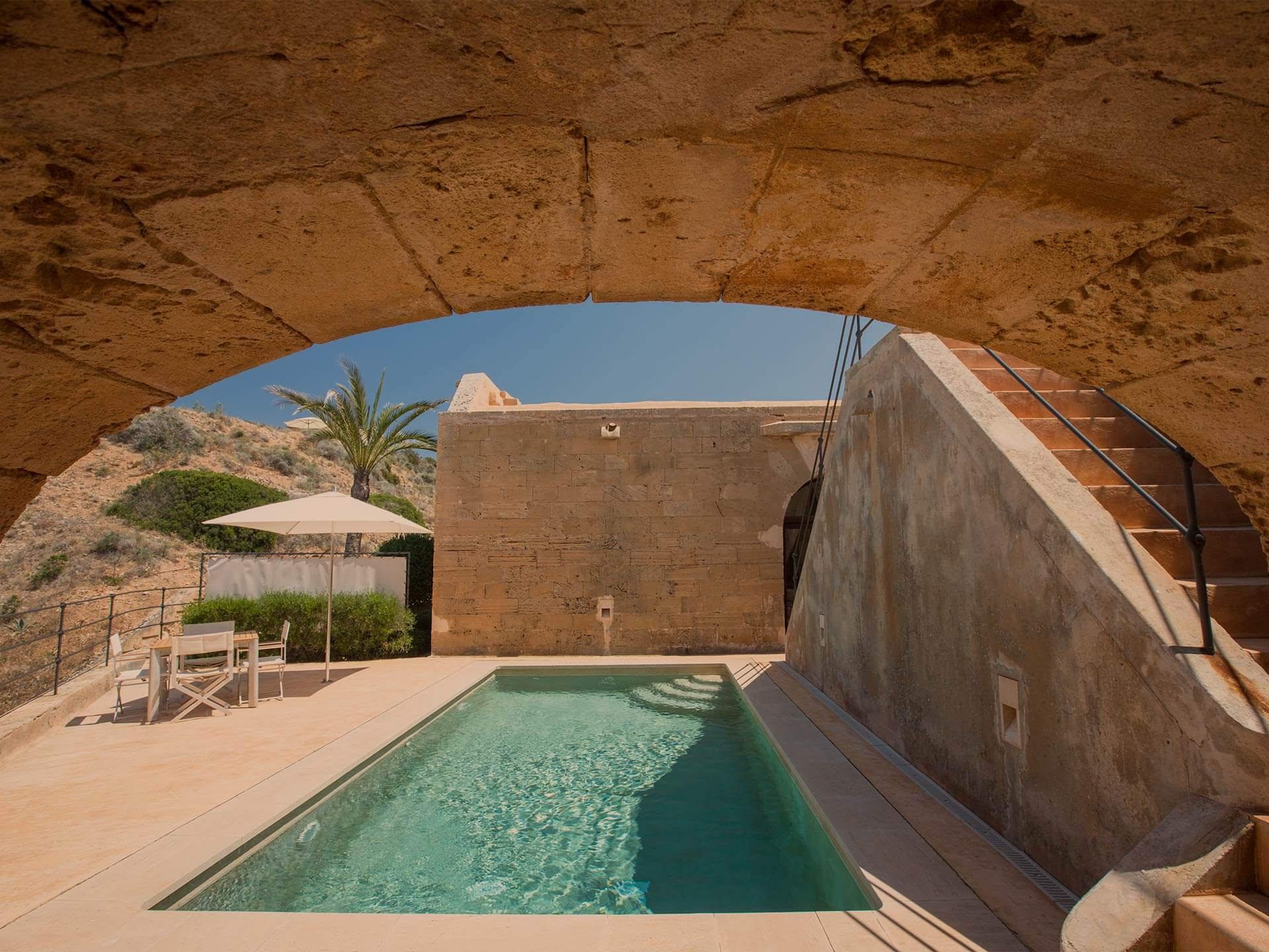 Cap Rocat: a carved stone archway frames a saltwater pool in turquoise, set within fortified walls overlooking the coast