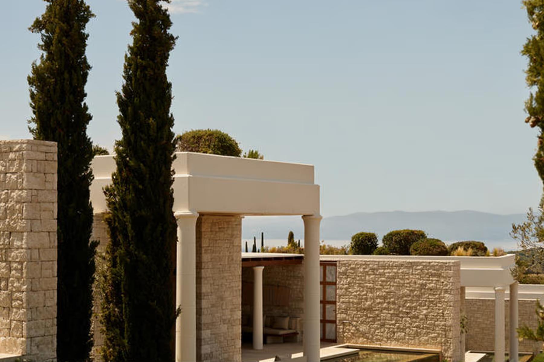 Amanzoe: outdoor terrace at dusk with columned structure and calm water below