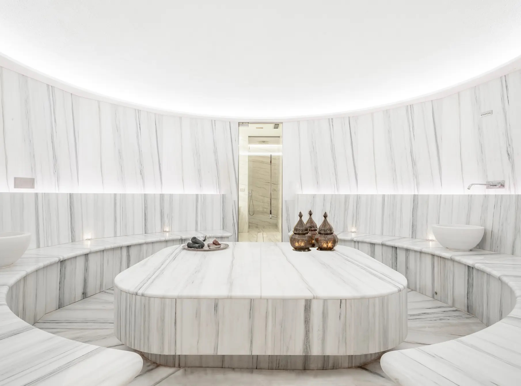 Spa relaxation room with circular bath in white chamber