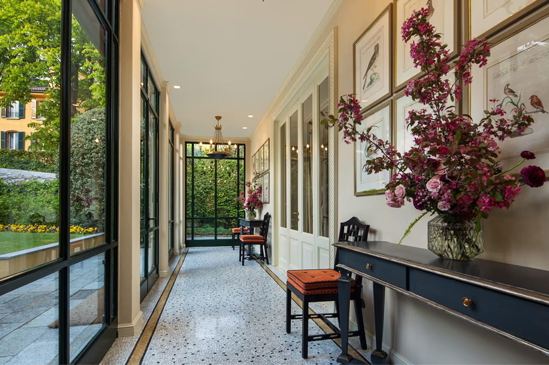 Villa d’Este: cream colonnade with flowering plants and lake view through open glass doors