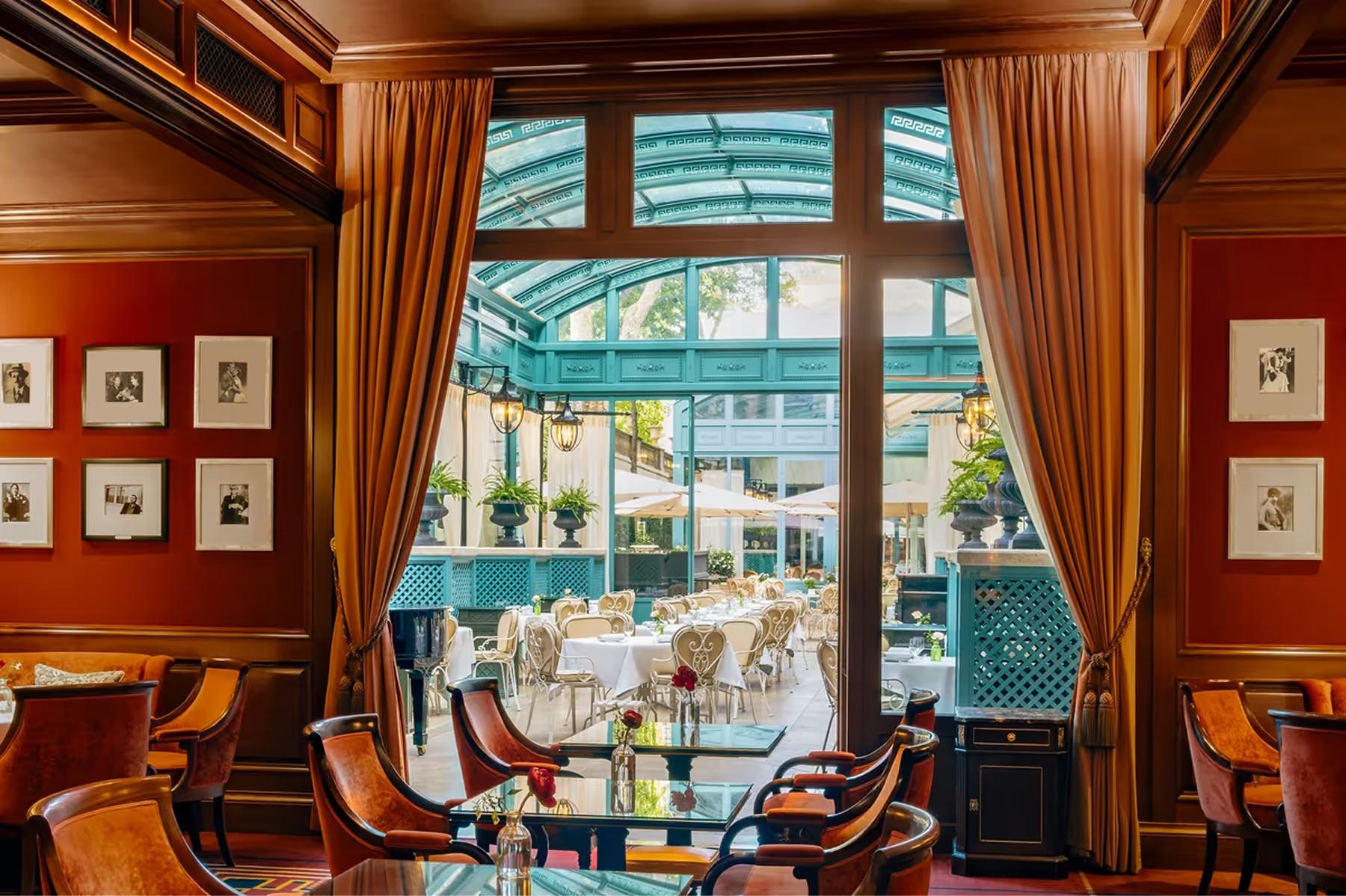 An intimate bar lounge with dark wood, green leather seating, and portrait artwork