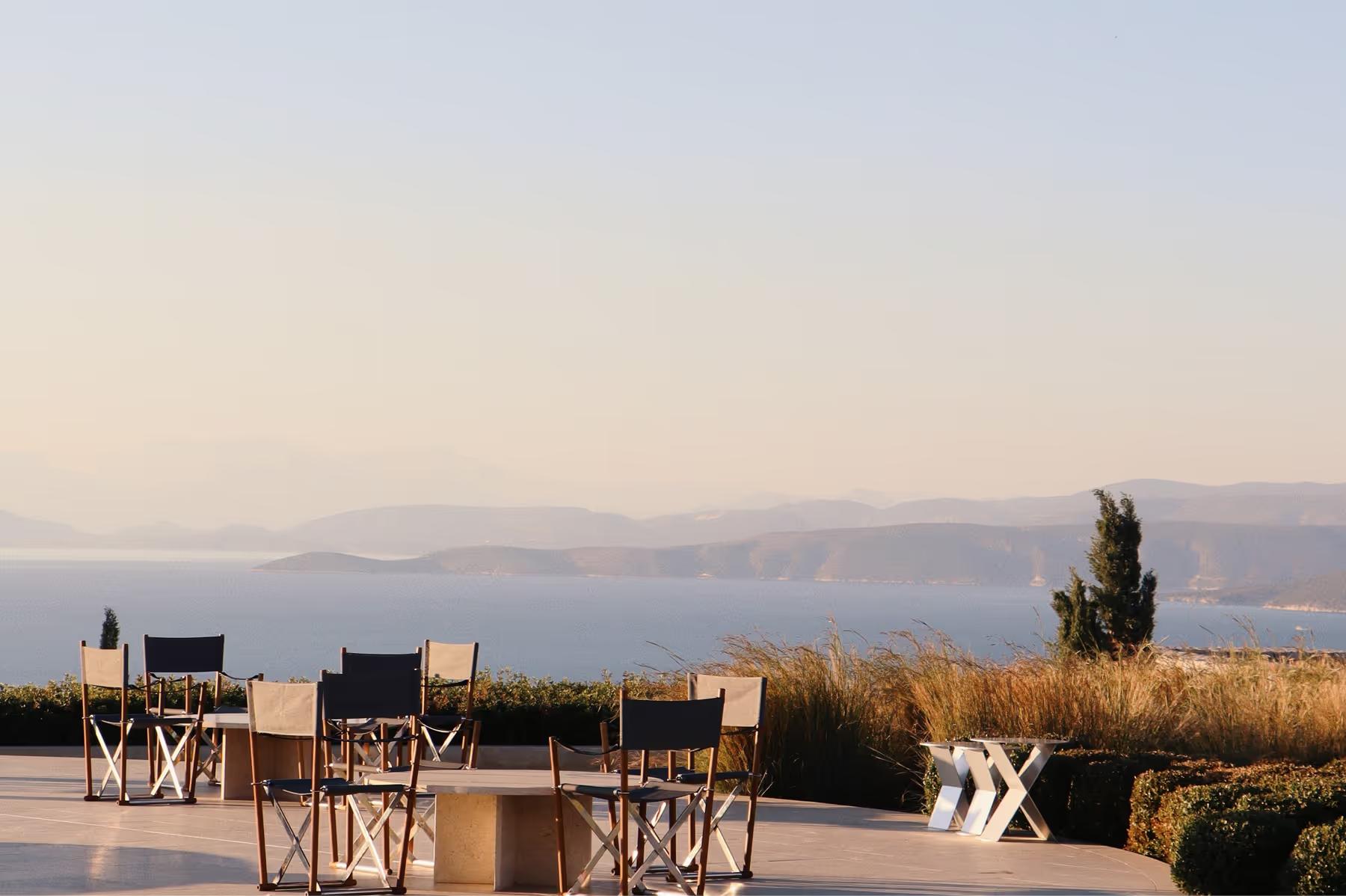 Sunset outdoor dinner setup with fire pit and seascape backdrop