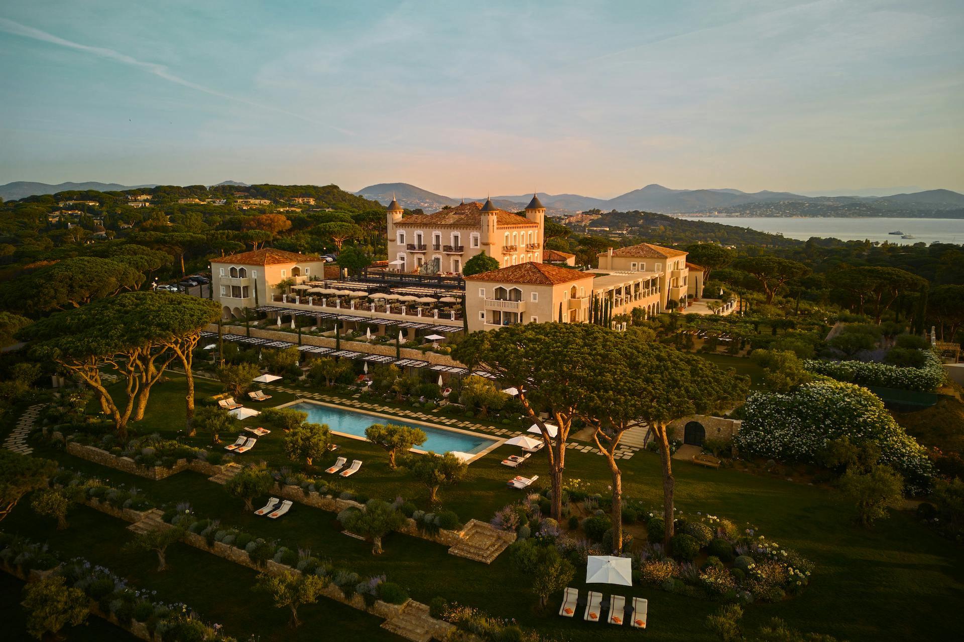 Hilltop château with manicured grounds and blue swimming pools overlooking Mediterranean coast
