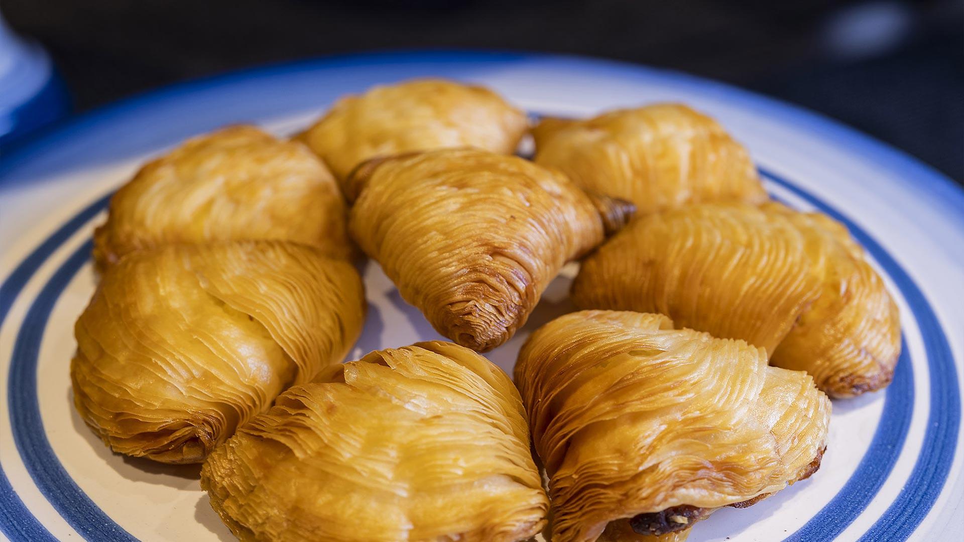 Golden pastries on a ceramic plate with blue-and-white trim, traditional Italian desserts