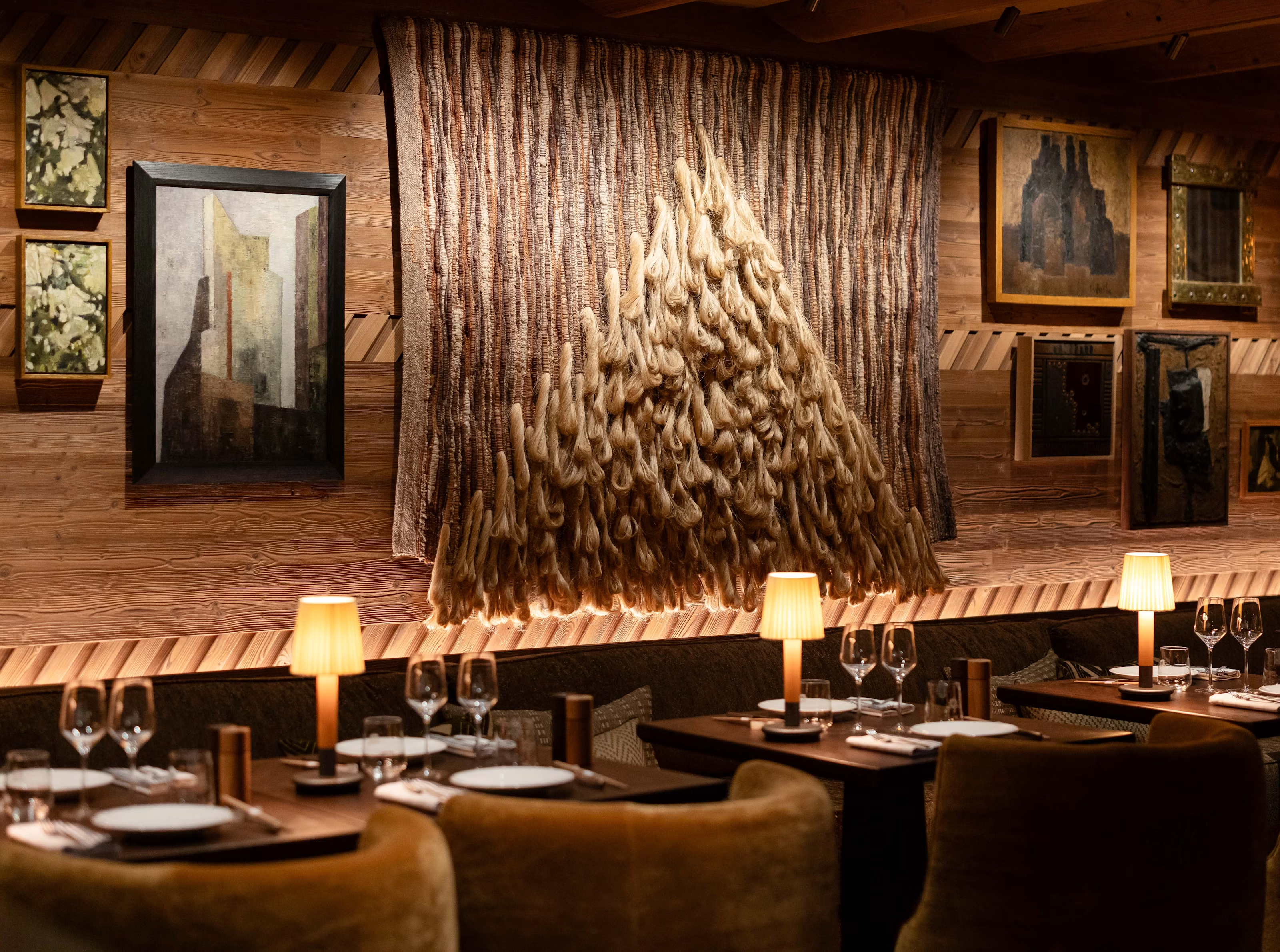 The dining room at L’Apogée Courchevel with a woven wall hanging above the tables