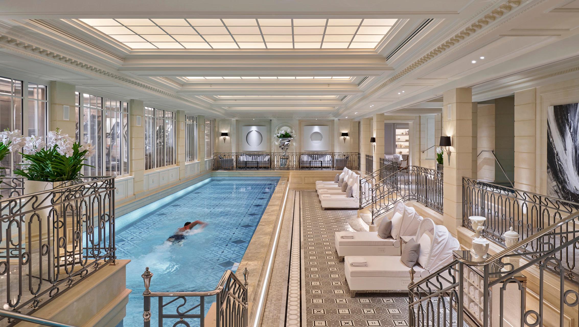 Four Seasons Hotel George V: an indoor swimming pool surrounded by beige loungers and glass railings