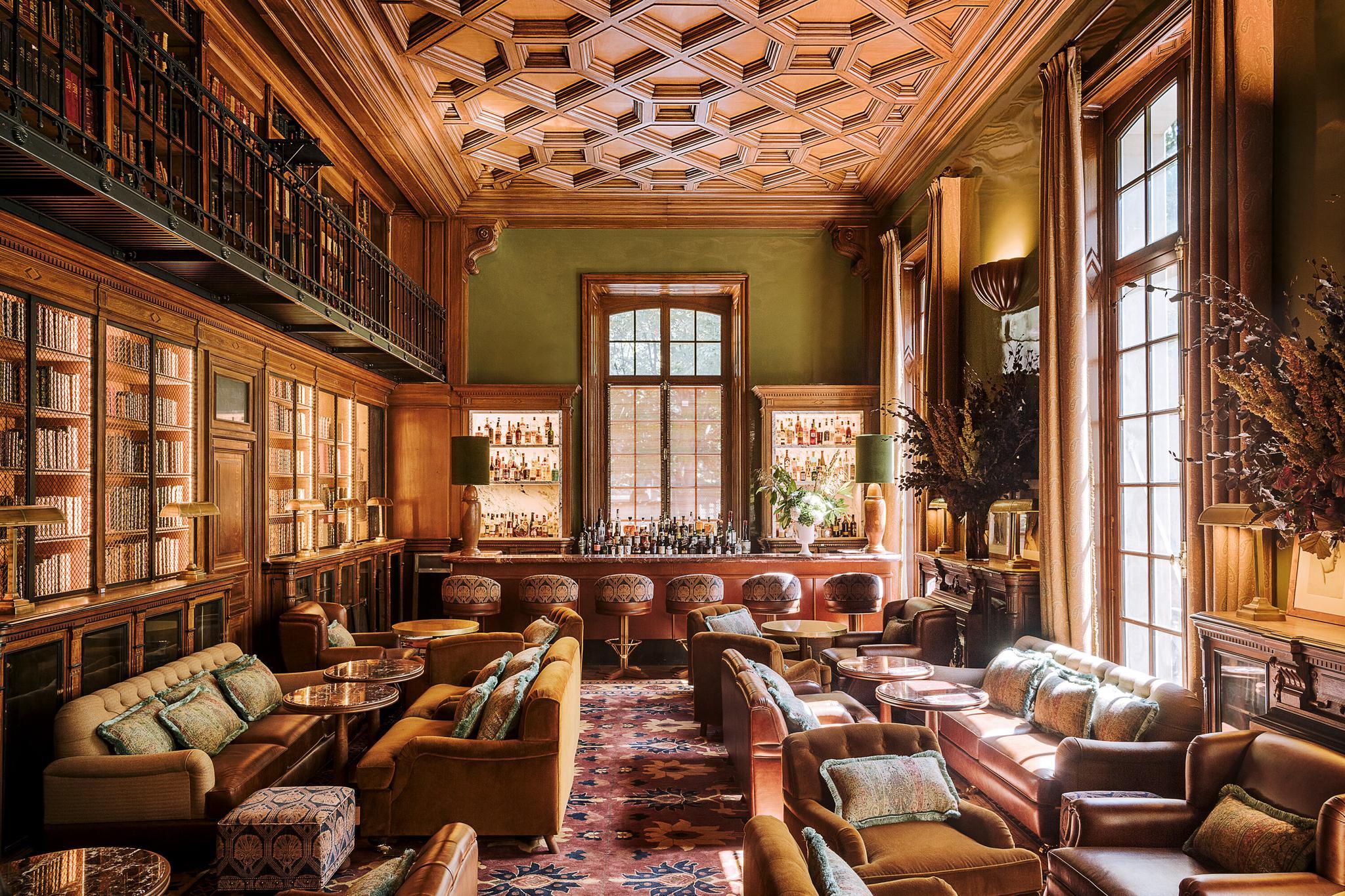 Saint James: lounge corner with marble-topped table, bronze sculptural base, and wood armchairs