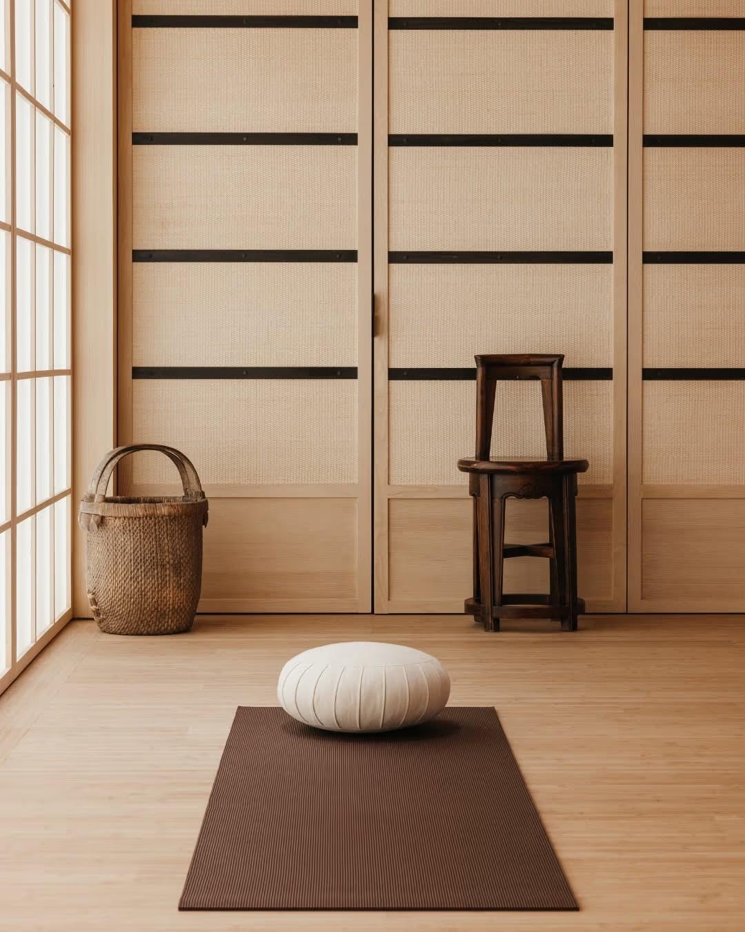 A quiet meditation room with a floor cushion on a dark mat