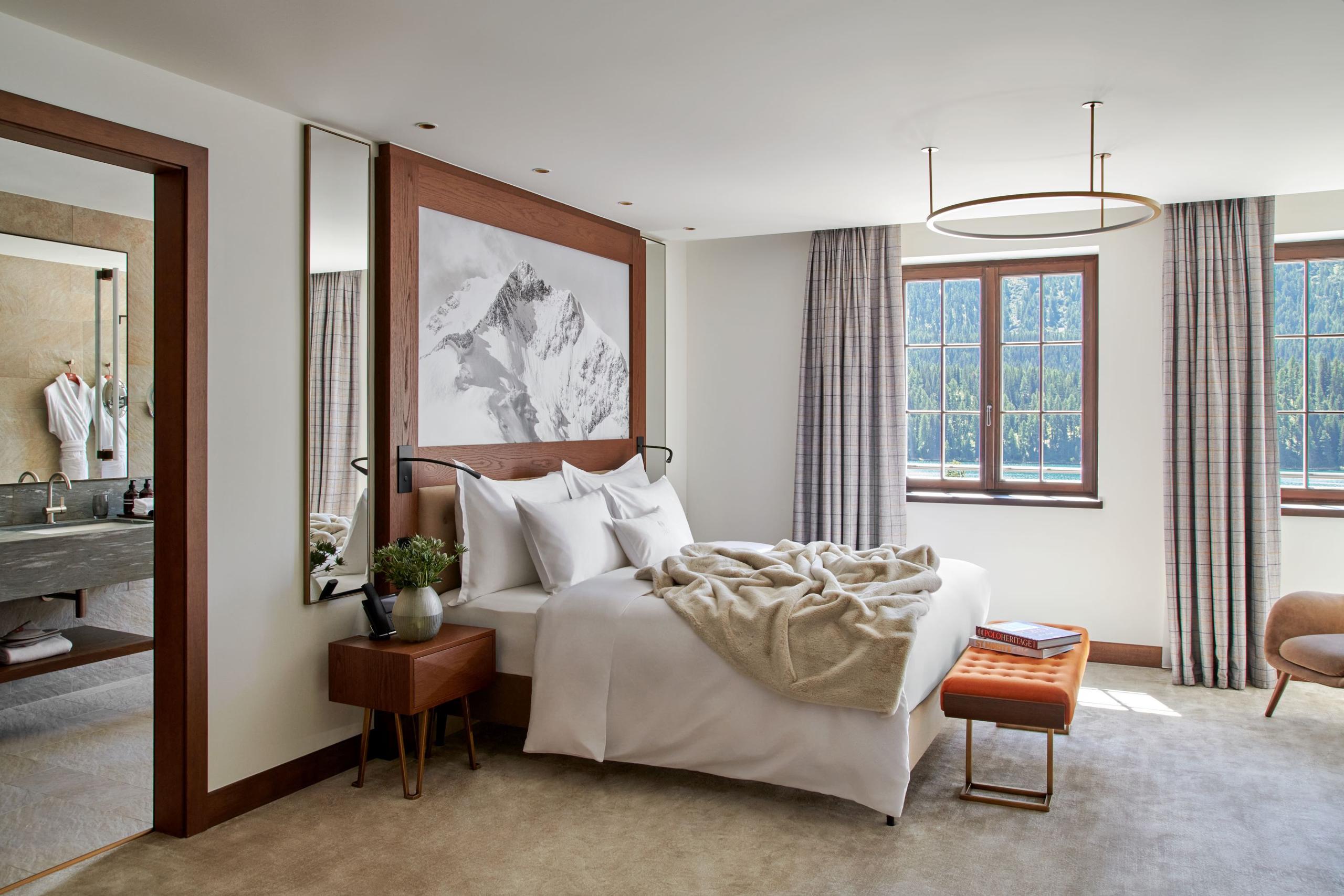 Bedroom with mirrored headboard, accent art, and cream furnishings facing mountain views
