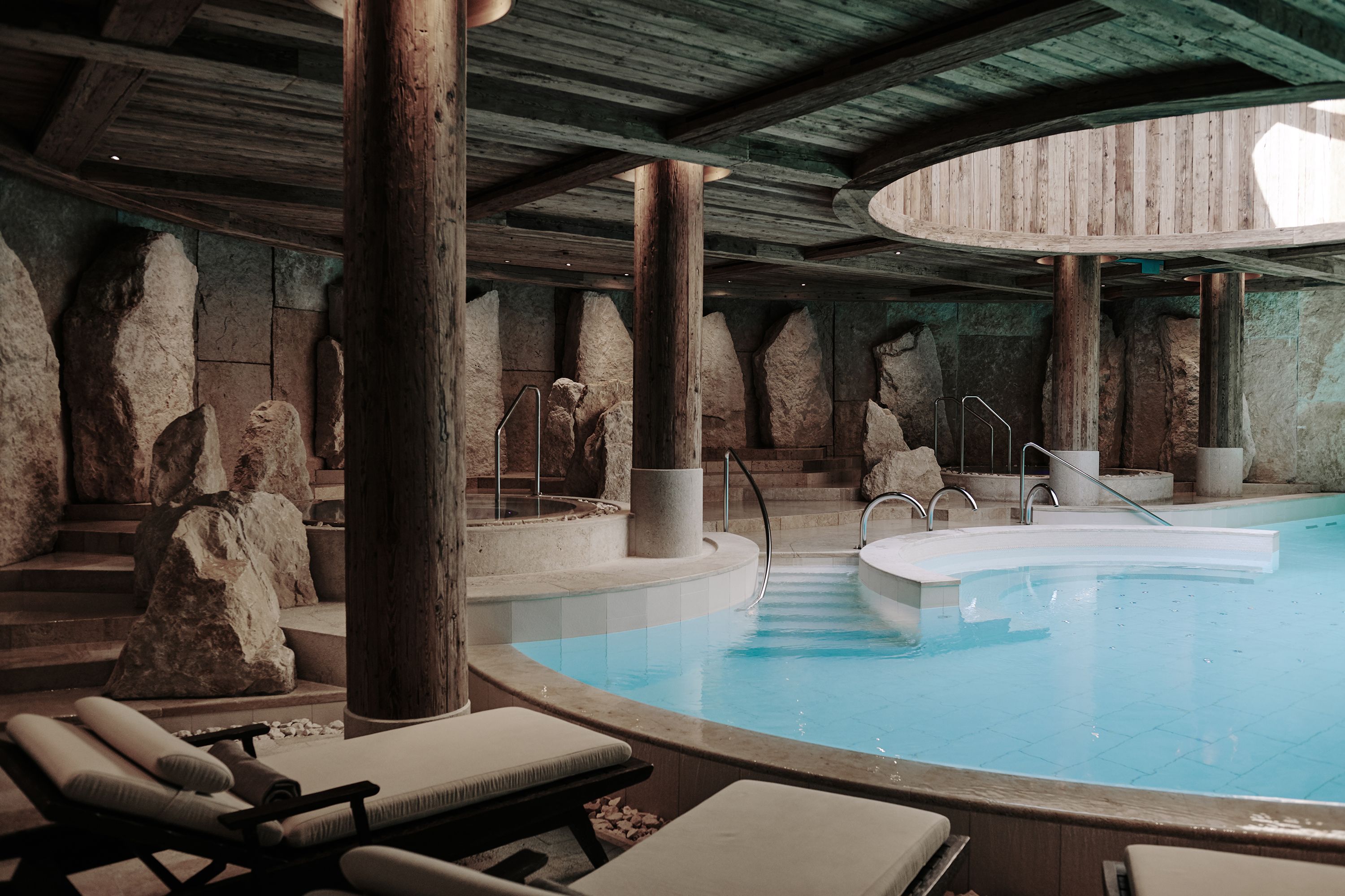 The grotto-style pool at The Alpina Gstaad, with boulders and timber columns