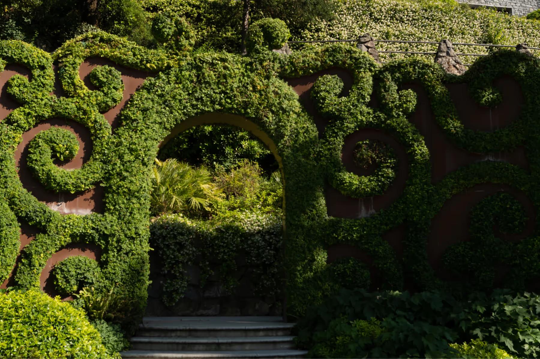 Mandarin Oriental, Lake Como: topiary hedging in decorative spiral forms with stone buildings visible through vegetation