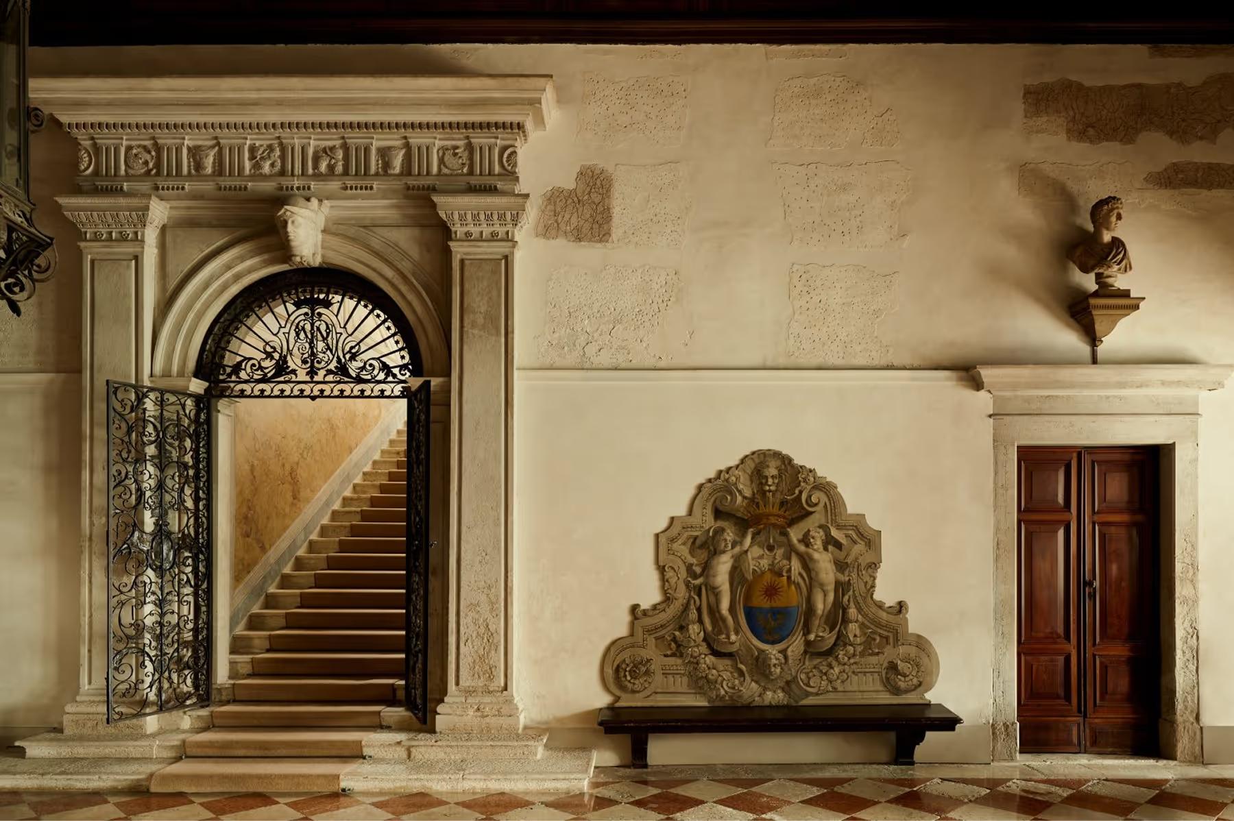 Aman Venice: the palazzo entrance hall with a monumental staircase, classical archway, and ornate stone sculpture