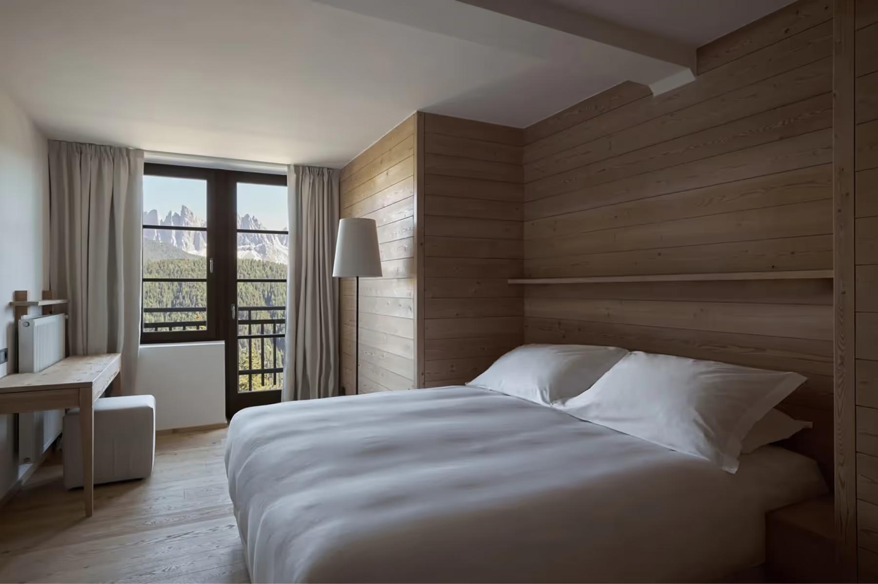 Forestis: a spa treatment room with a stone bench, minimal natural wood cabinetry, and mountain views